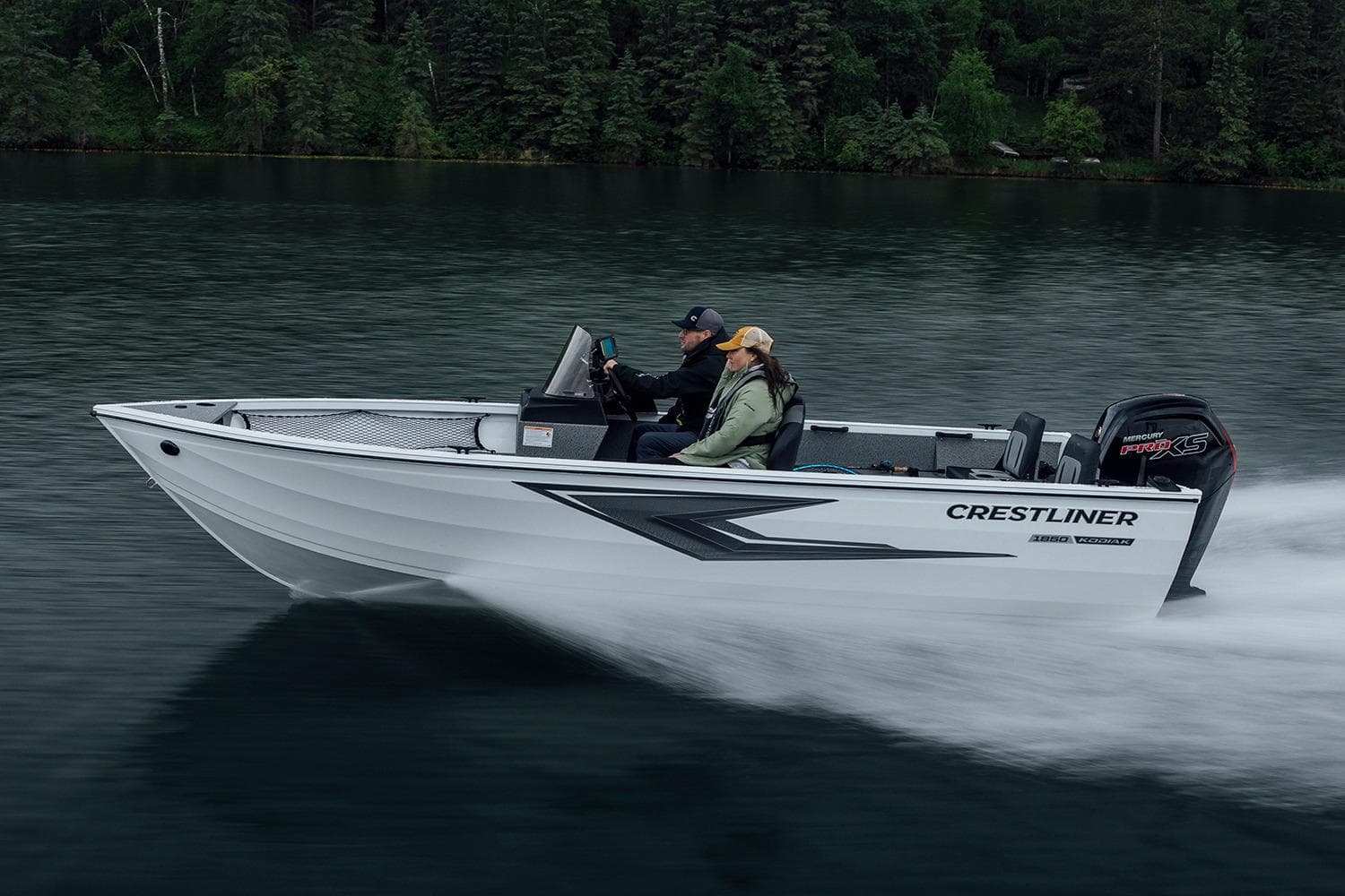 Manufacturer Provided Image: 2026 Crestliner 1850 Kodiak SC boat cruising on a serene lake with lush forest backdrop.