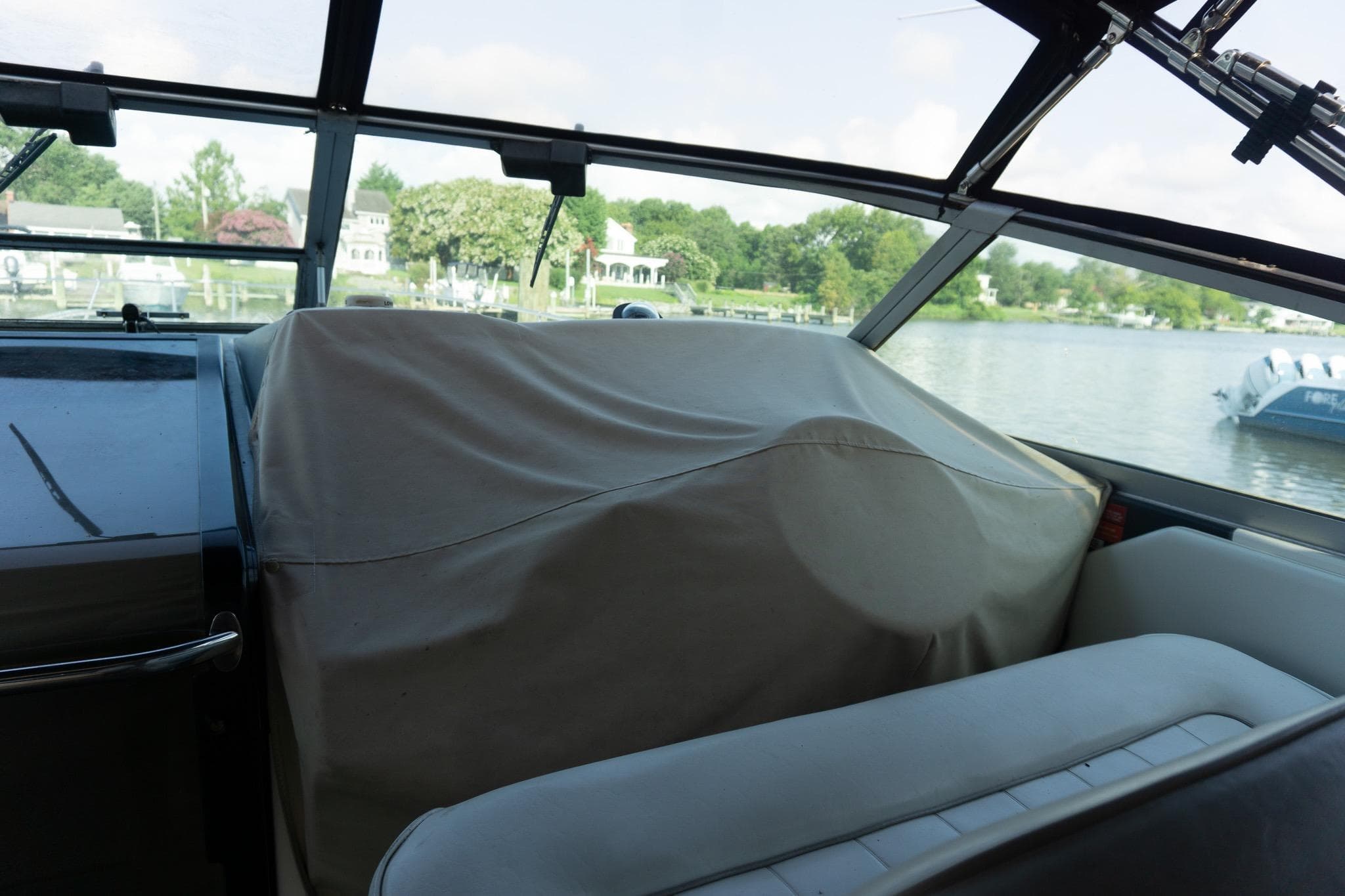 Interior view of a 1993 Sea Ray 400 Express Cruiser with covered dashboard, overlooking a serene lake.