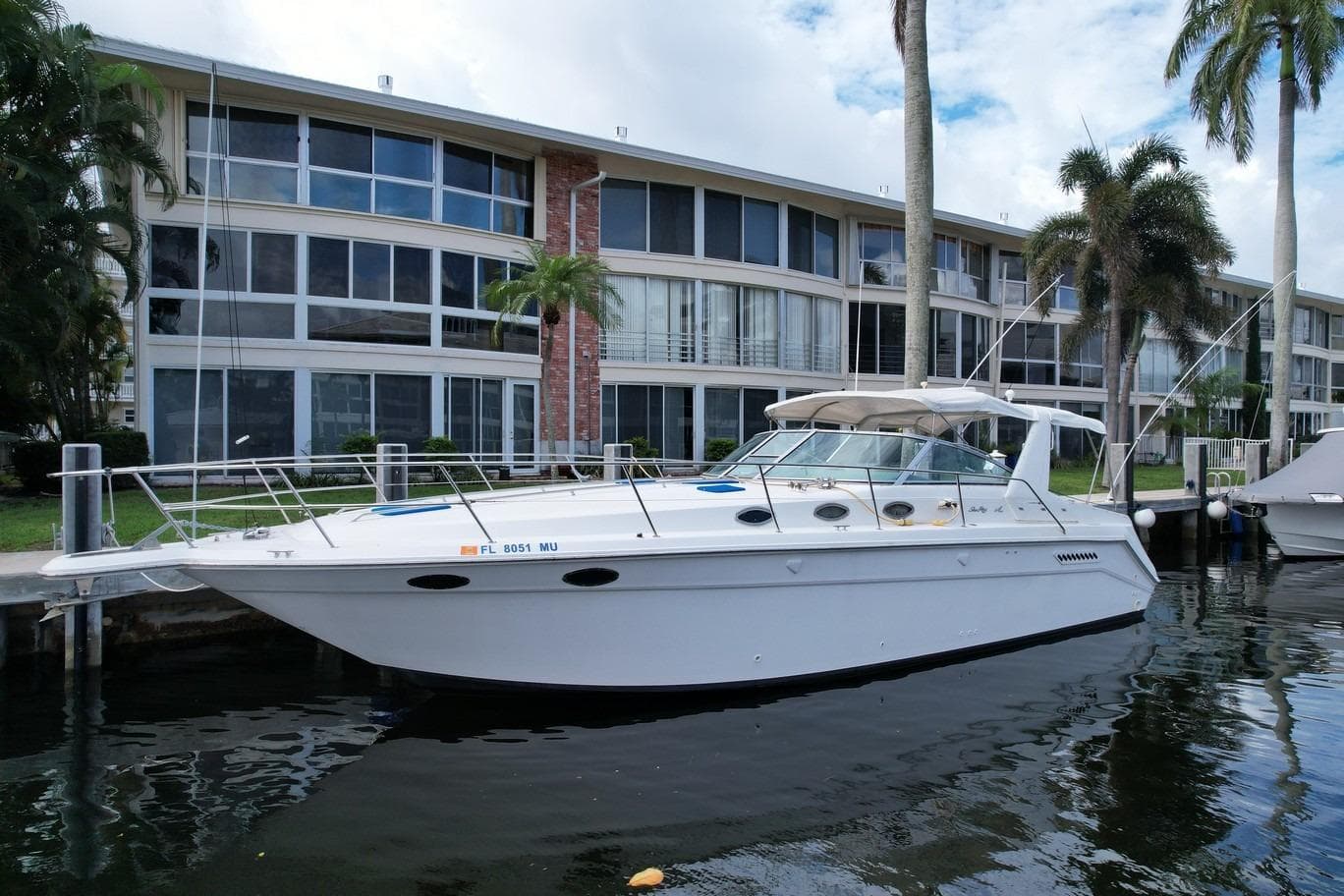 1994 Sea Ray 370 Express Cruiser docked near modern waterfront apartments.