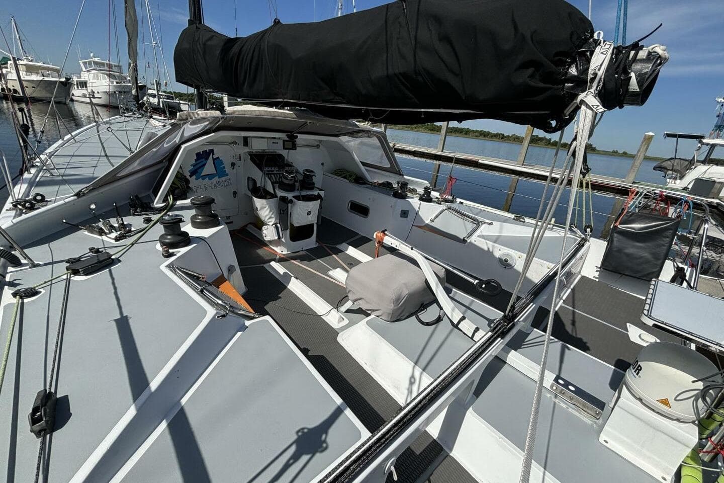 2009 Akilaria RC2 Class 40 sailboat cockpit, docked at marina under clear blue sky.