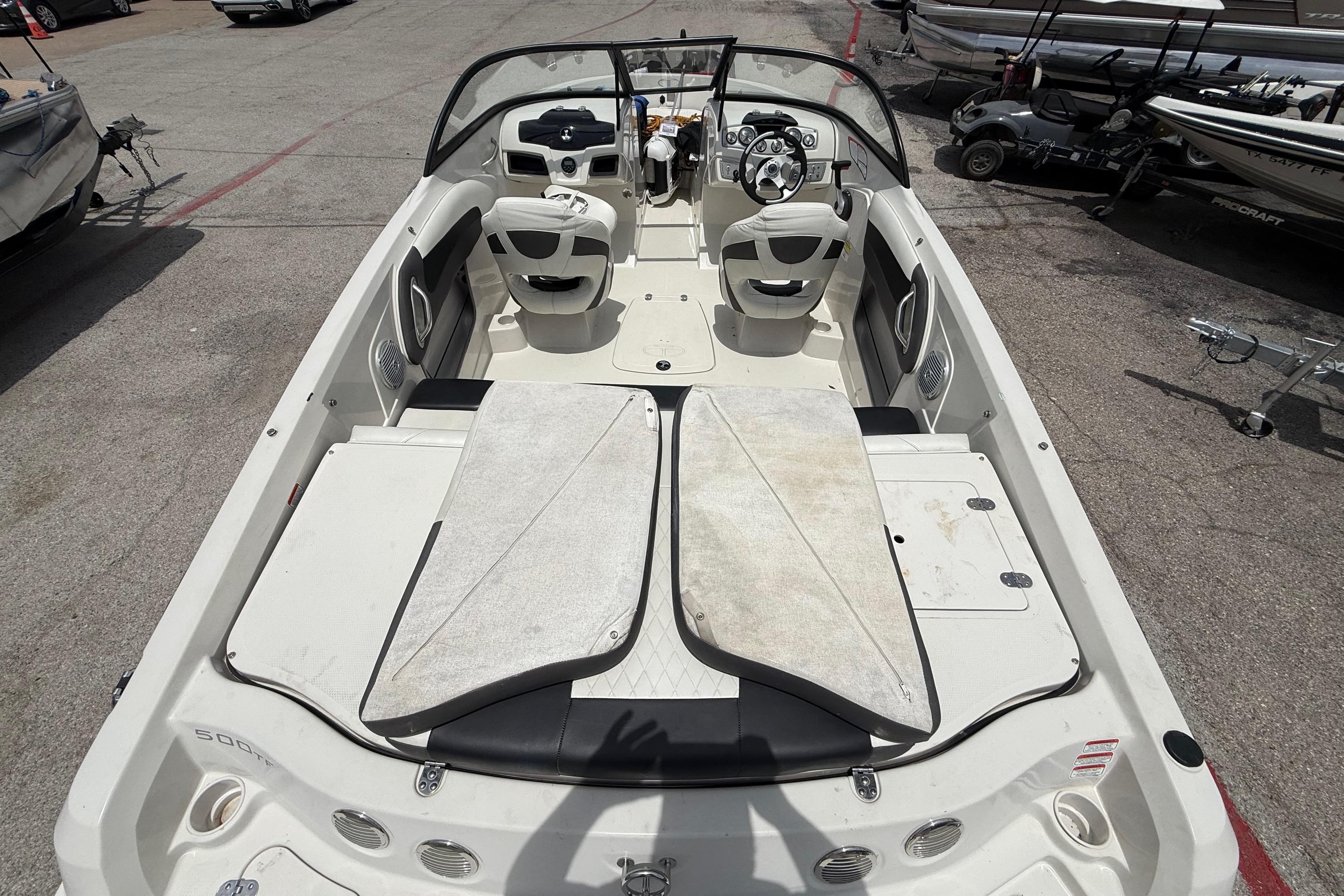 2016 Tahoe 500 TF boat interior with seating and steering wheel, parked on pavement.