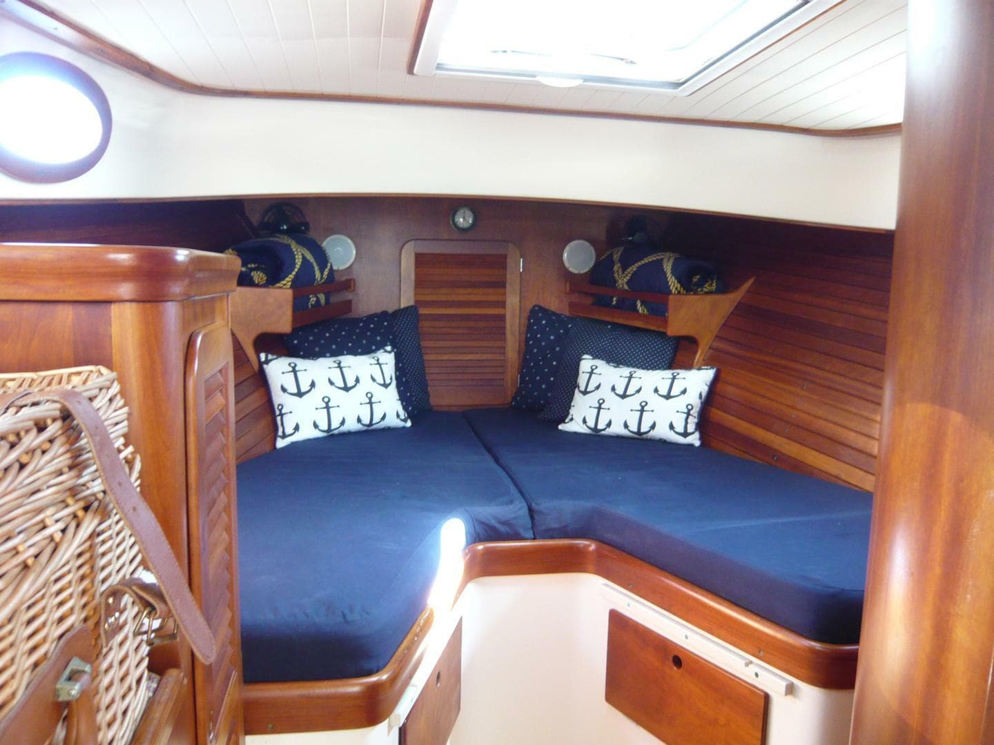 Cozy cabin interior of 1998 Hinckley 36 Classic with nautical-themed pillows and wooden finish.