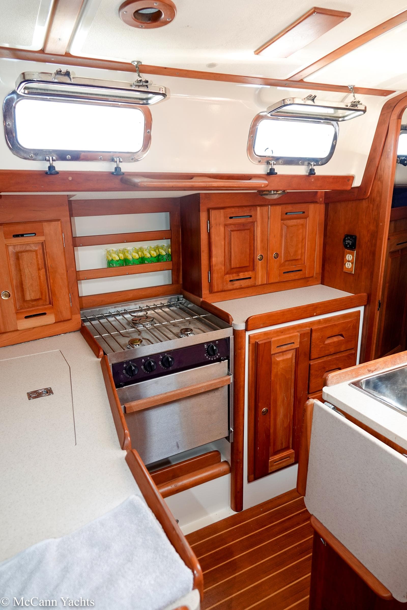 Interior of 2002 Tartan 3700 sailboat with wooden cabinetry and compact kitchen area.