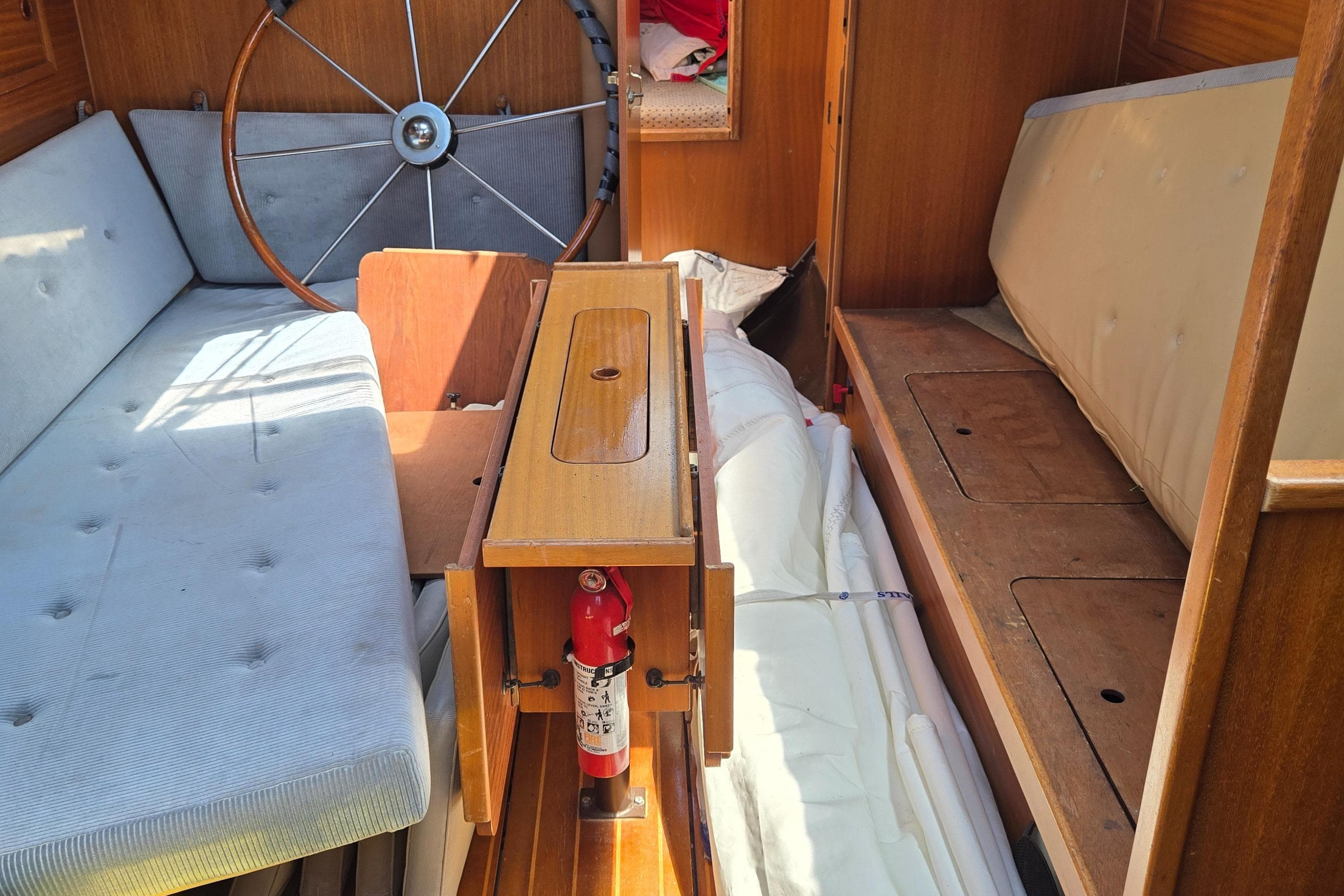 Interior of 1987 Dehler Optima 34 sailboat with wooden furnishings and steering wheel.