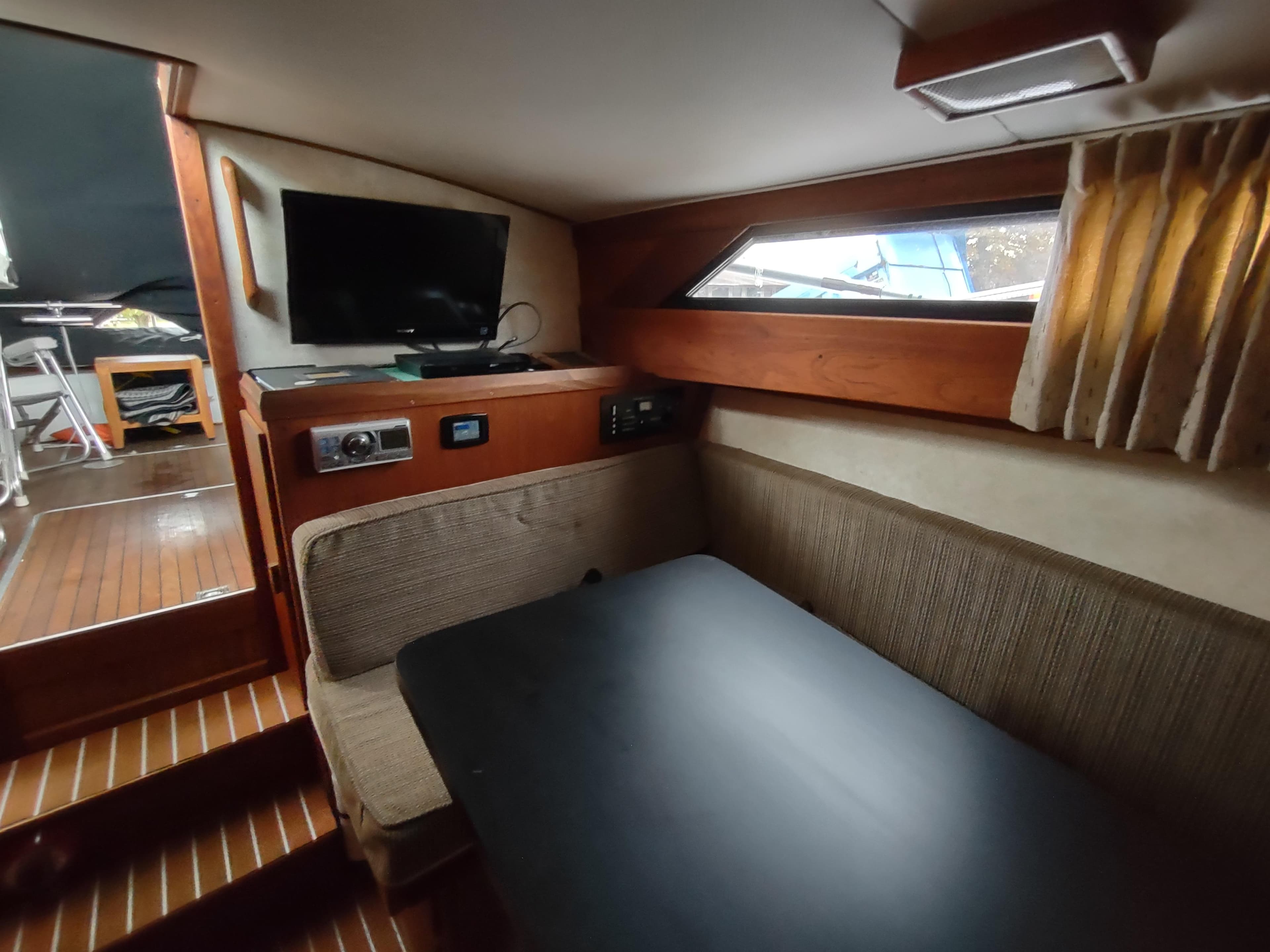 1976 Trojan 260 Hardtop Express cabin interior with seating, table, and TV.