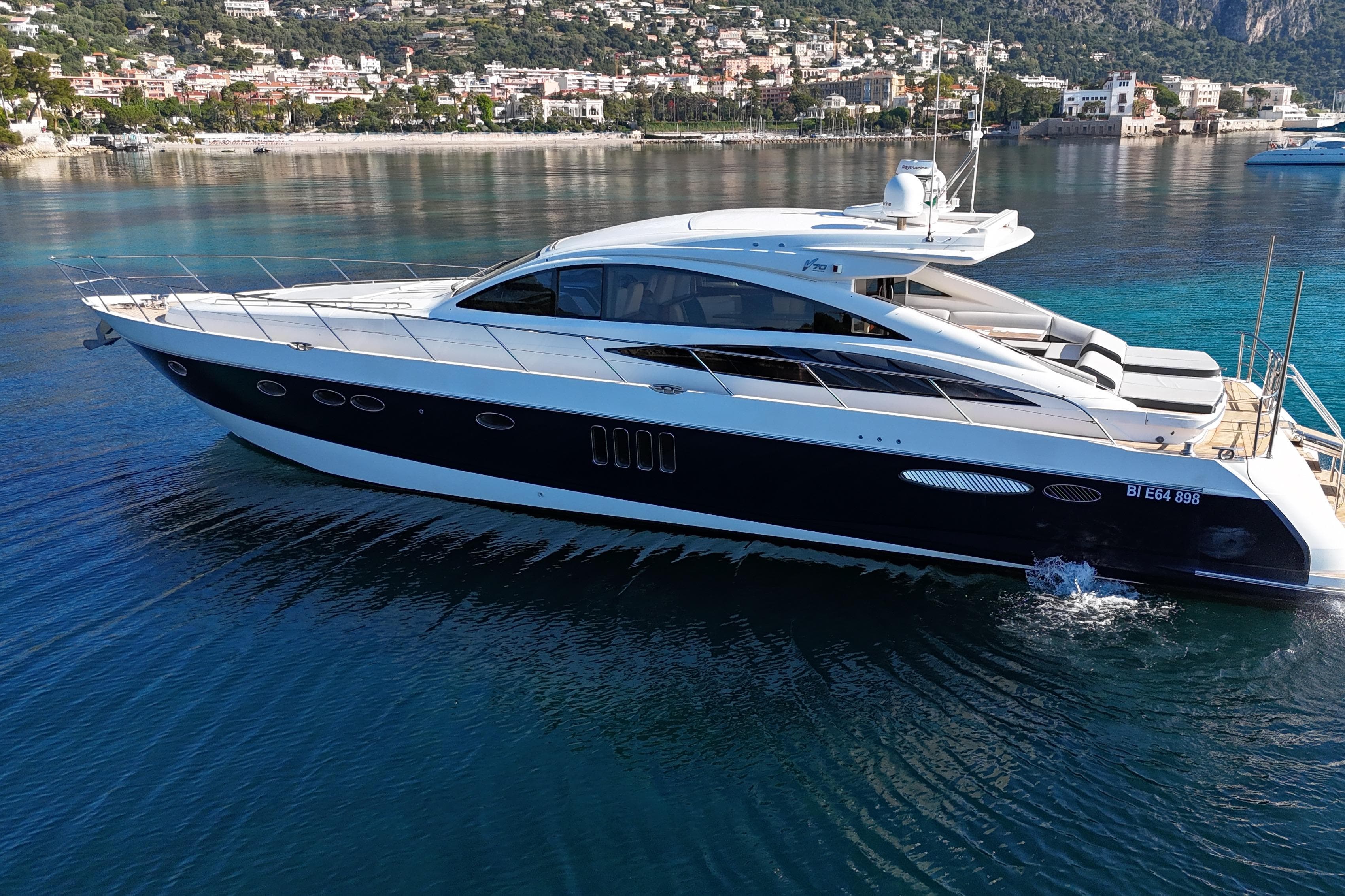 Luxury 2006 Princess V70 yacht cruising on clear blue waters near a scenic coastline.