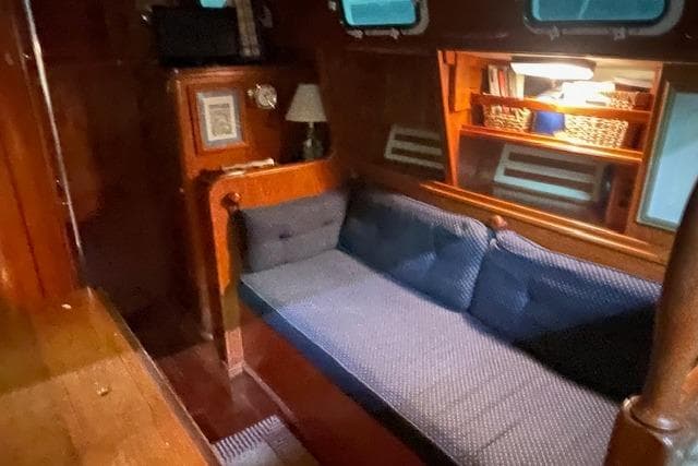Cozy interior of 1984 Endeavour 35 sailboat with blue cushioned seating and wooden accents.