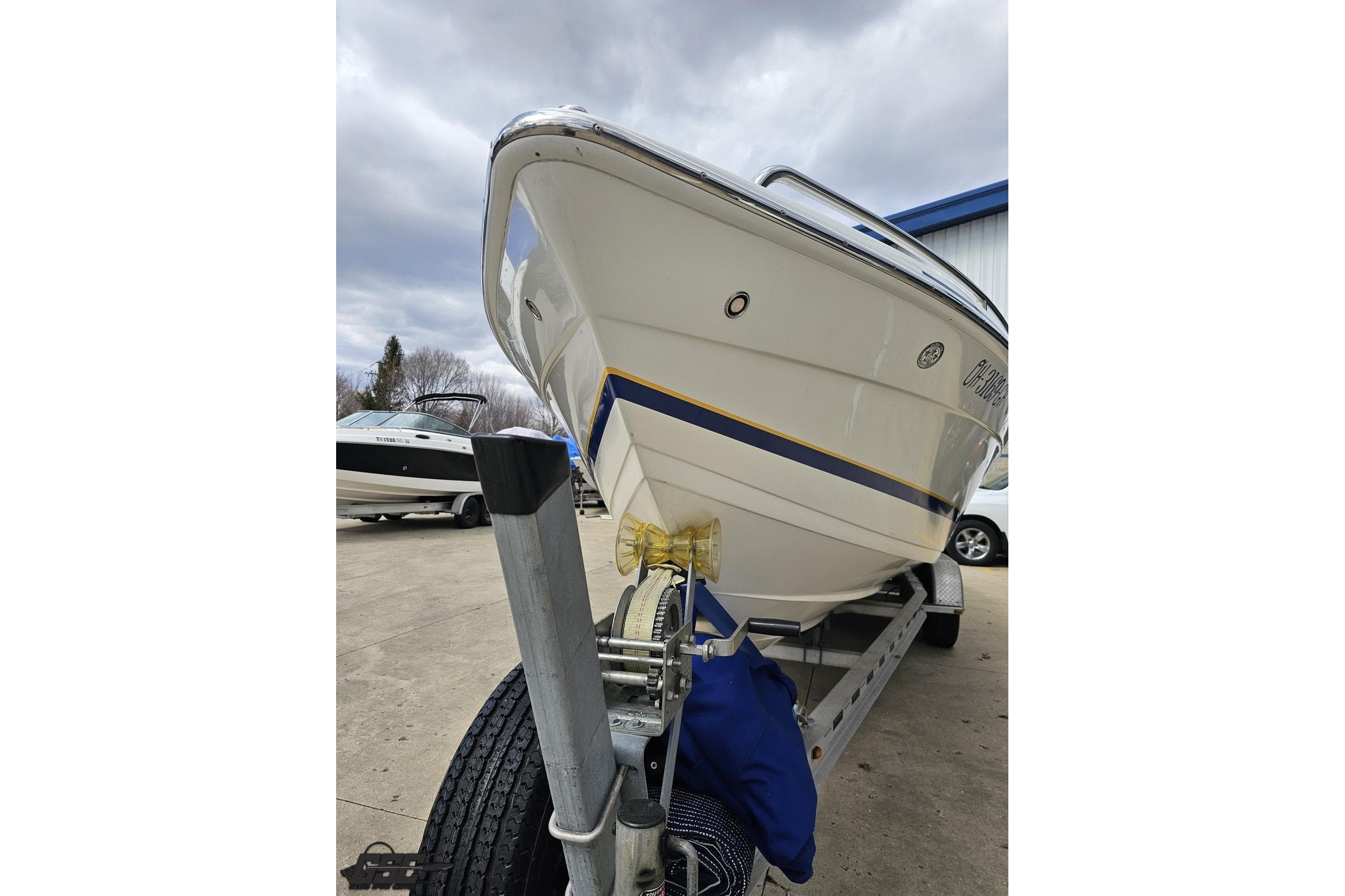 2008 Formula 271 FASTech boat on trailer, parked outdoors under cloudy sky.