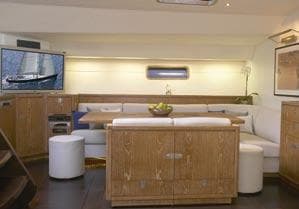 Luxurious yacht interior with wooden furnishings, white seating, and a wall-mounted TV. CNB 104, 2002 model.