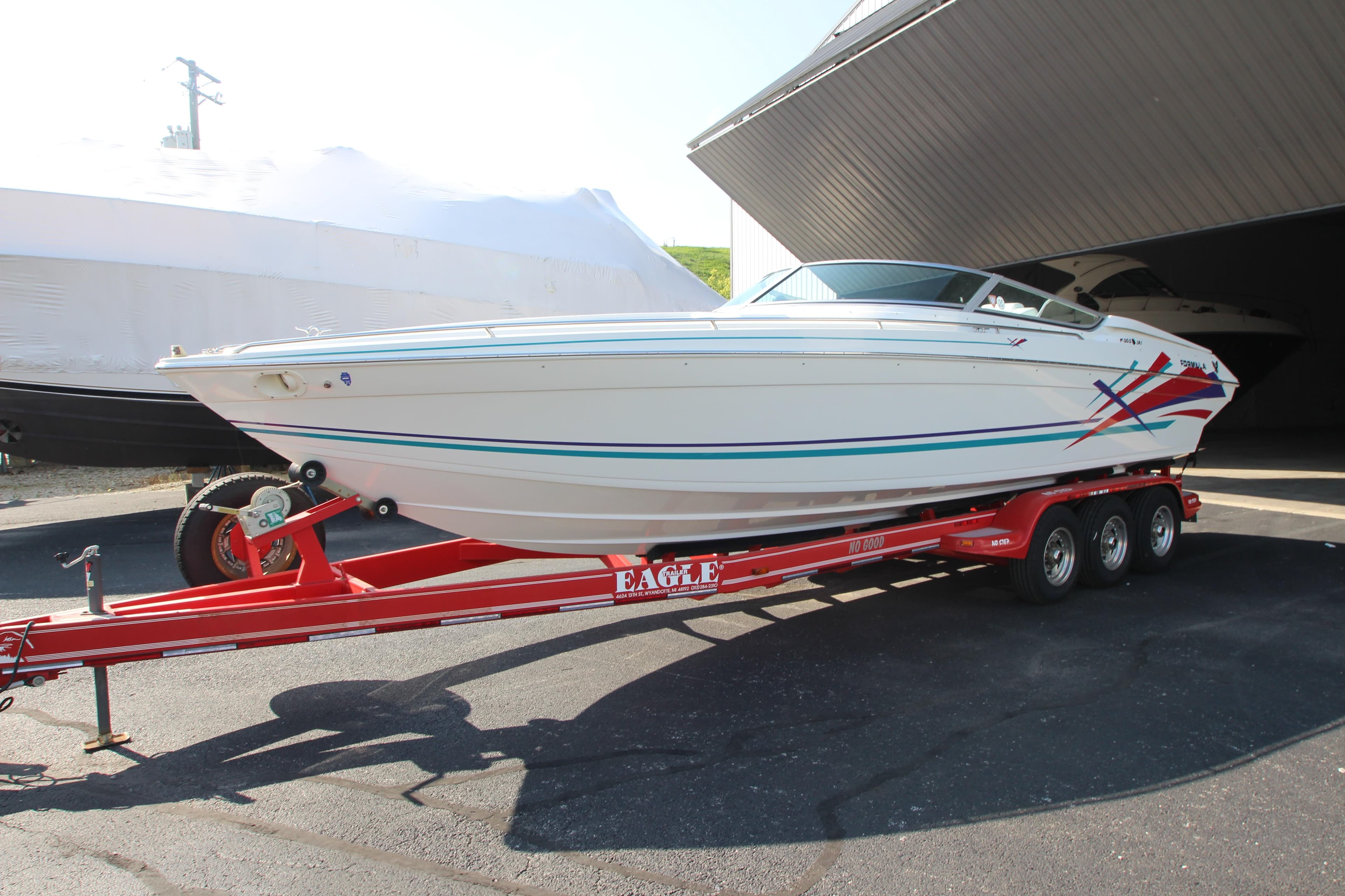 1995 Formula SR1 303 speedboat on red trailer, parked outdoors.