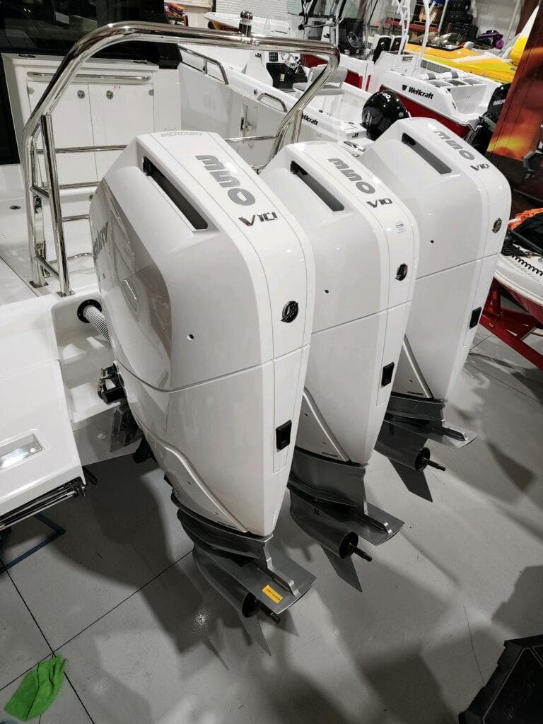 2024 Wellcraft 355 Commuter with triple outboard engines in a showroom.
