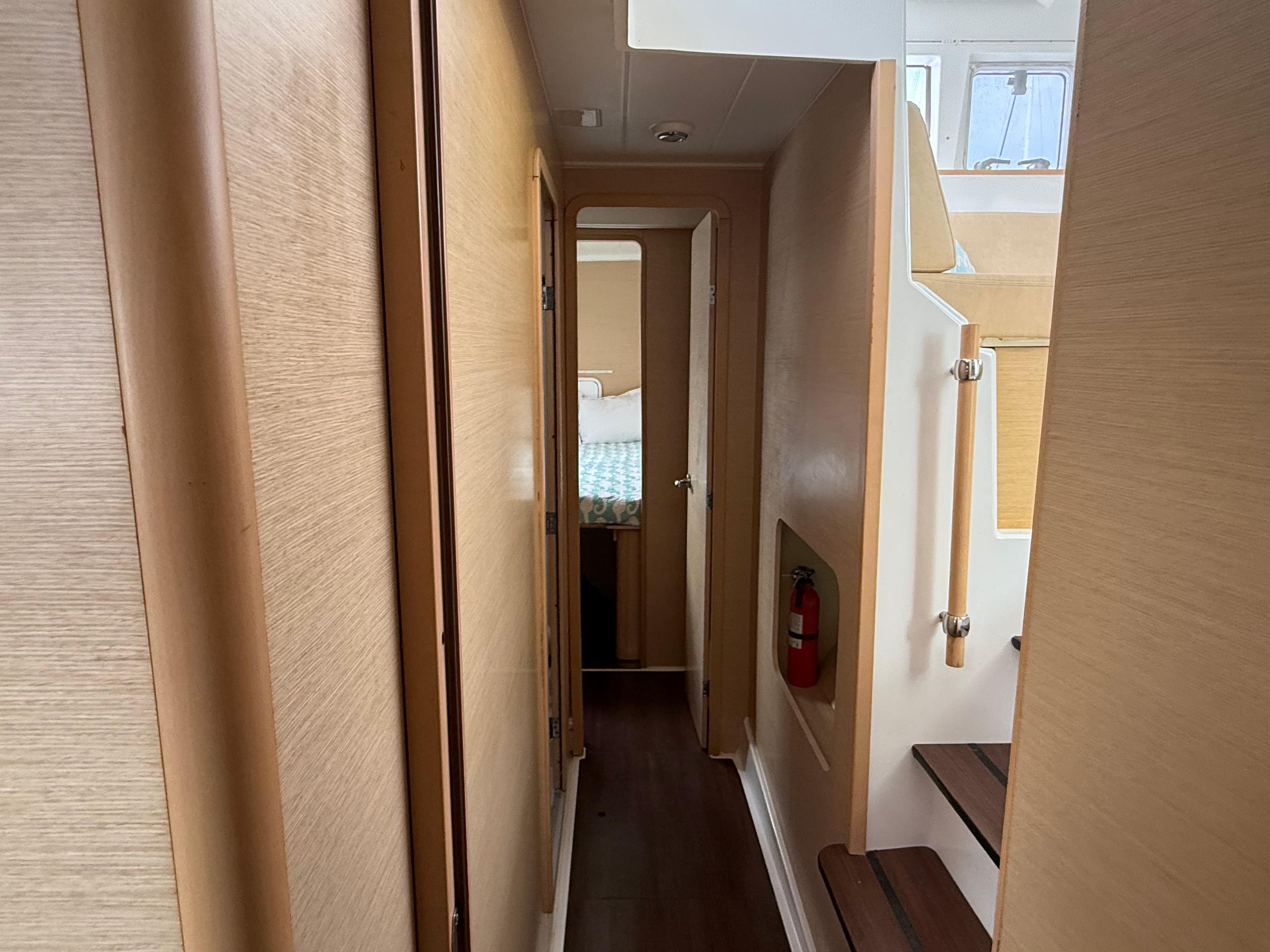 Narrow hallway inside 2010 Lagoon 400 Owner's Version yacht, featuring wooden paneling and stairs.
