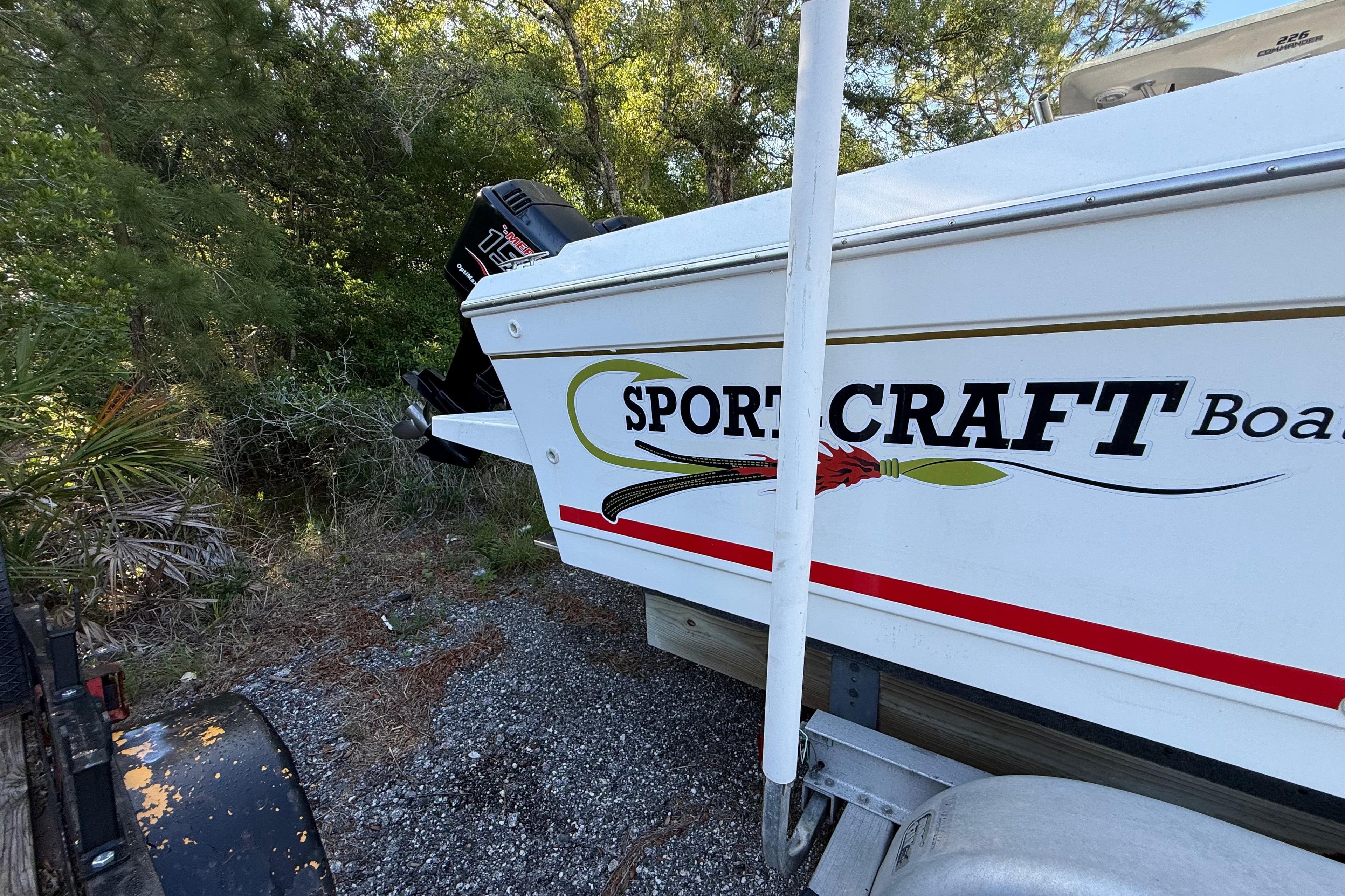 2000 Sport-Craft 241 Walk Around boat on trailer, parked in wooded area.