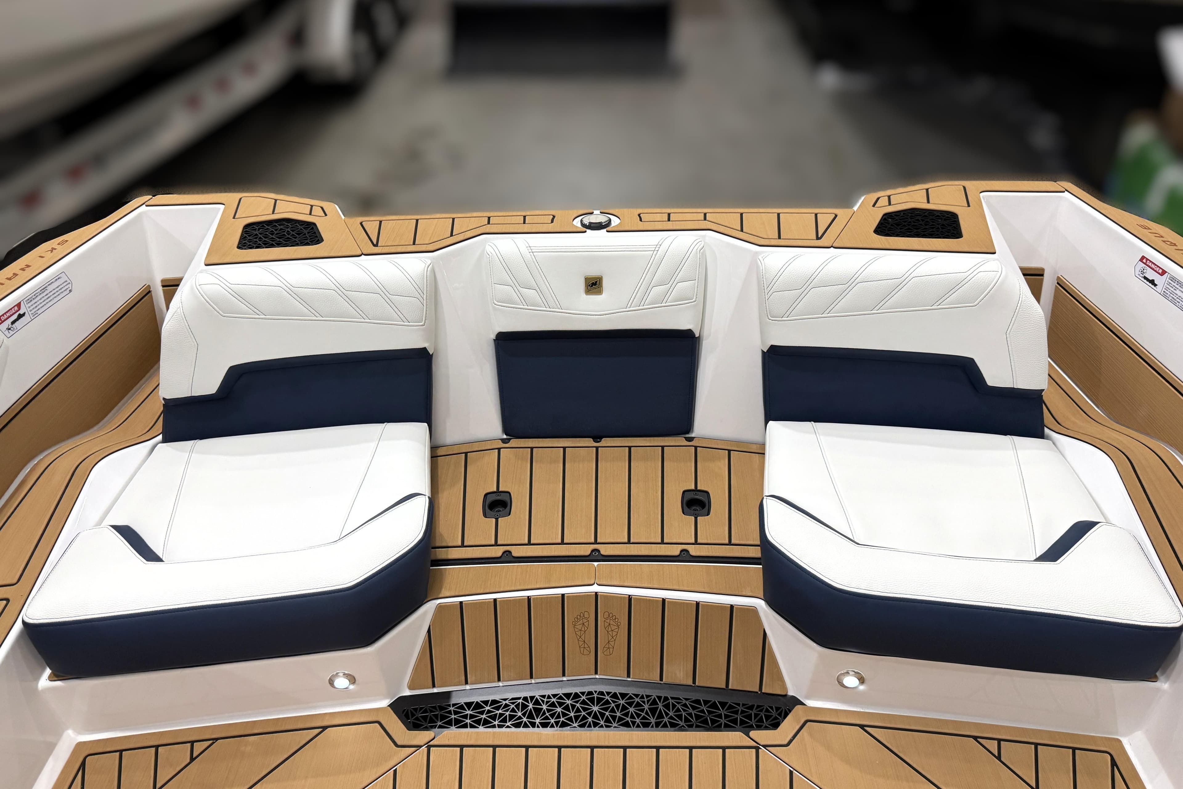 2026 Nautique Ski Nautique boat interior with white and navy seating, teak flooring.