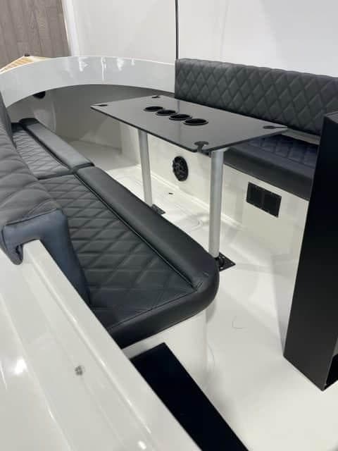 2023 Vision Marine Technologies Fantail 217 interior with black quilted seating and sleek table design.