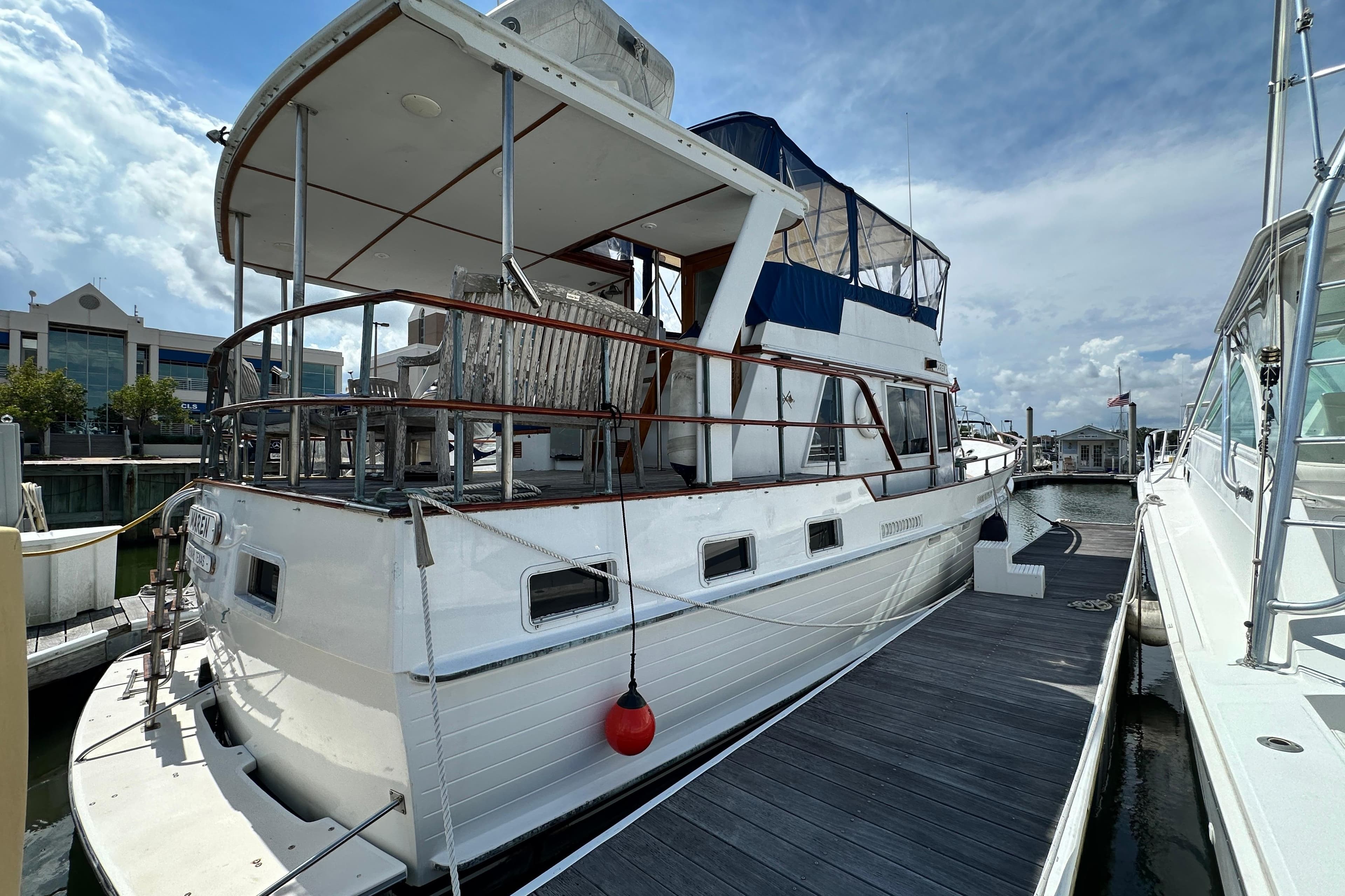 1980 Island Gypsy Flush Aft Deck Trawler-Motor Yacht docked at marina under cloudy sky.