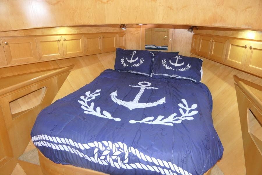 Cozy cabin bedroom in 1999 Hampton 490 Pilothouse with nautical-themed bedding.