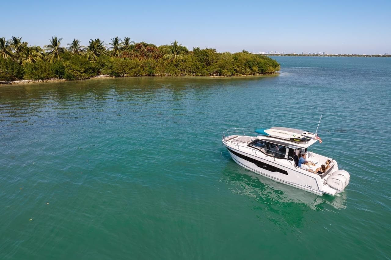 2025 Jeanneau NC 895 Series 2 cruising on serene tropical waters near lush island.