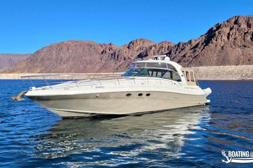 2005 Sea Ray 500 Sundancer yacht on a serene lake with rocky mountains.