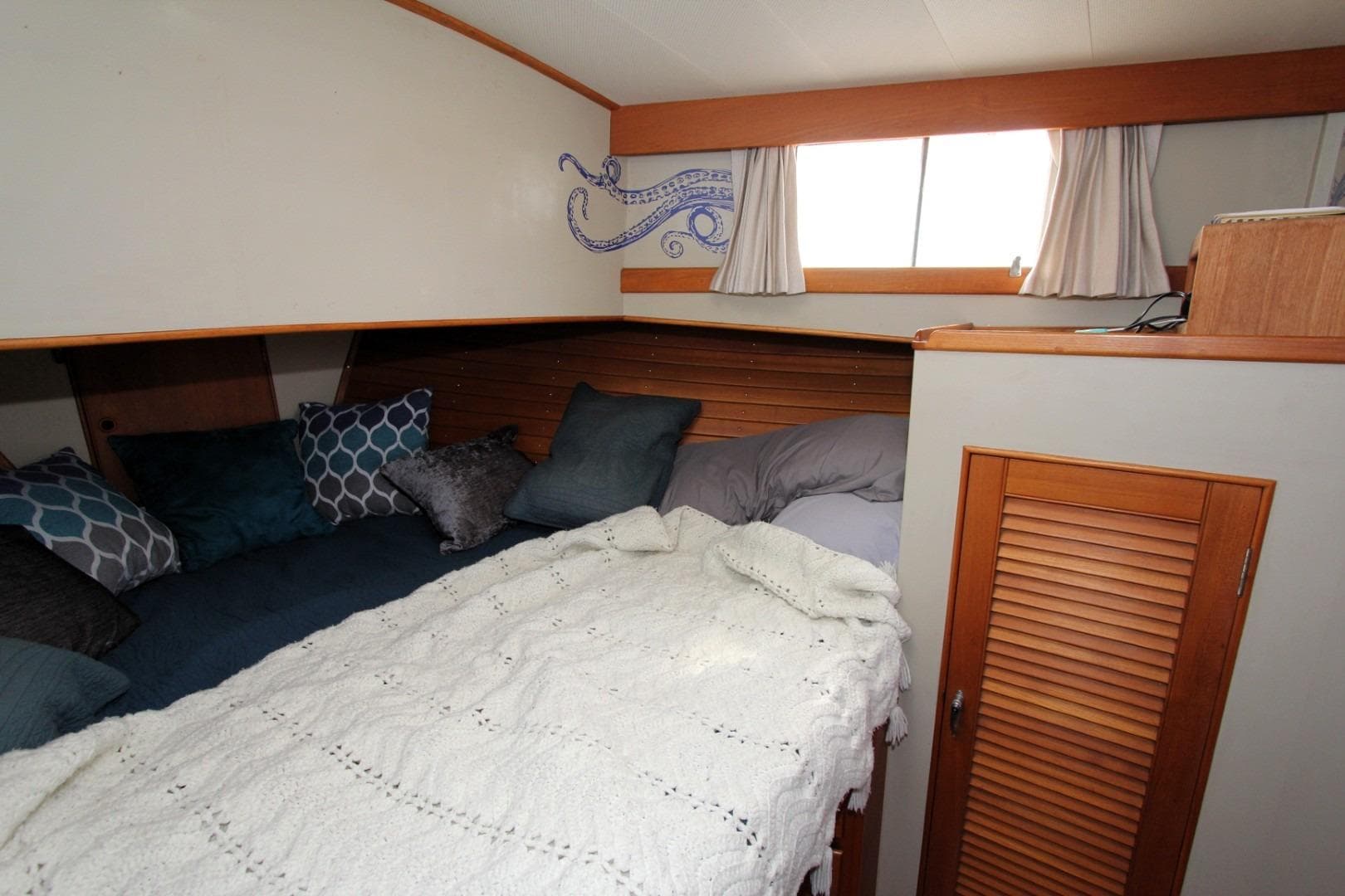 Cozy cabin interior of 1982 Grand Banks 42 Europa with bed and decorative pillows.