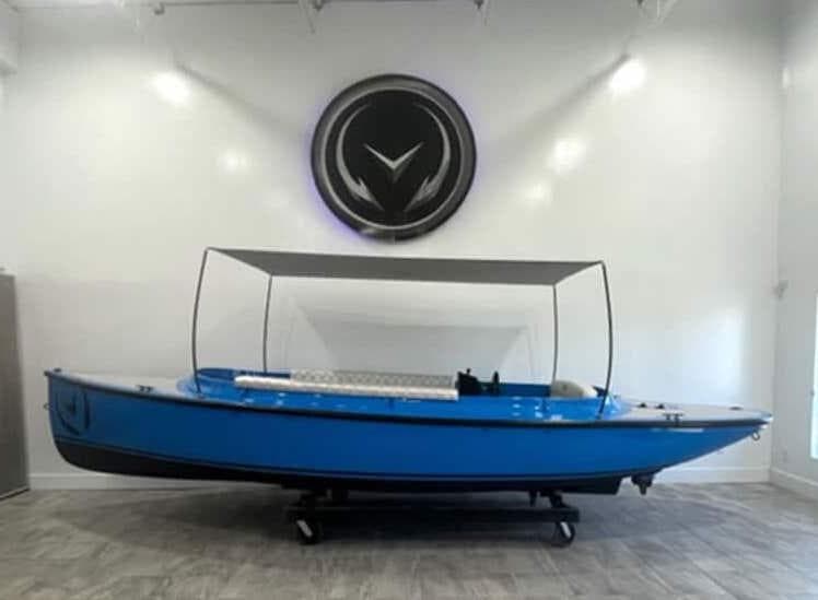 2024 Vision Marine Technologies Fantail 217 electric boat in showroom, blue with canopy.
