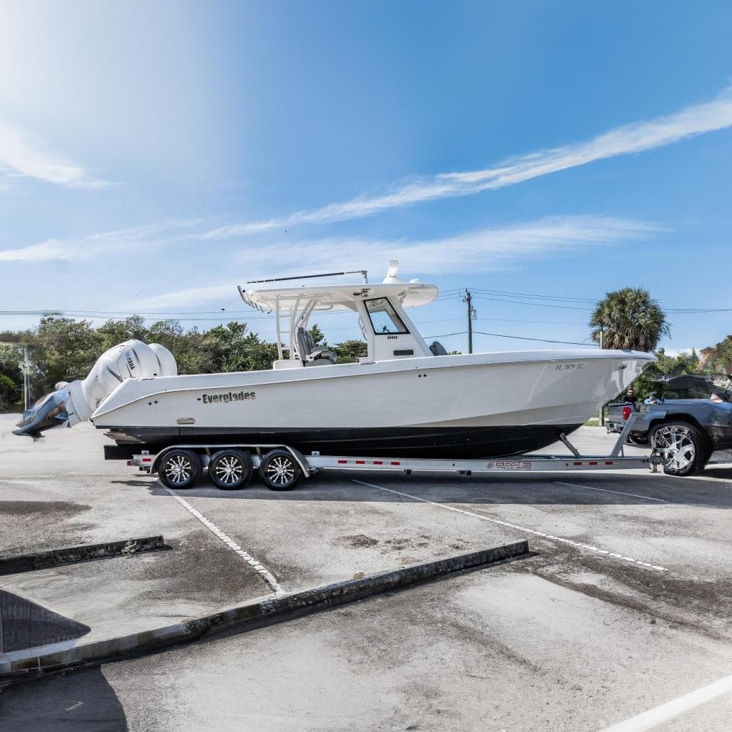 2021 Everglades 335 Center Console boat on trailer in parking lot under clear sky.