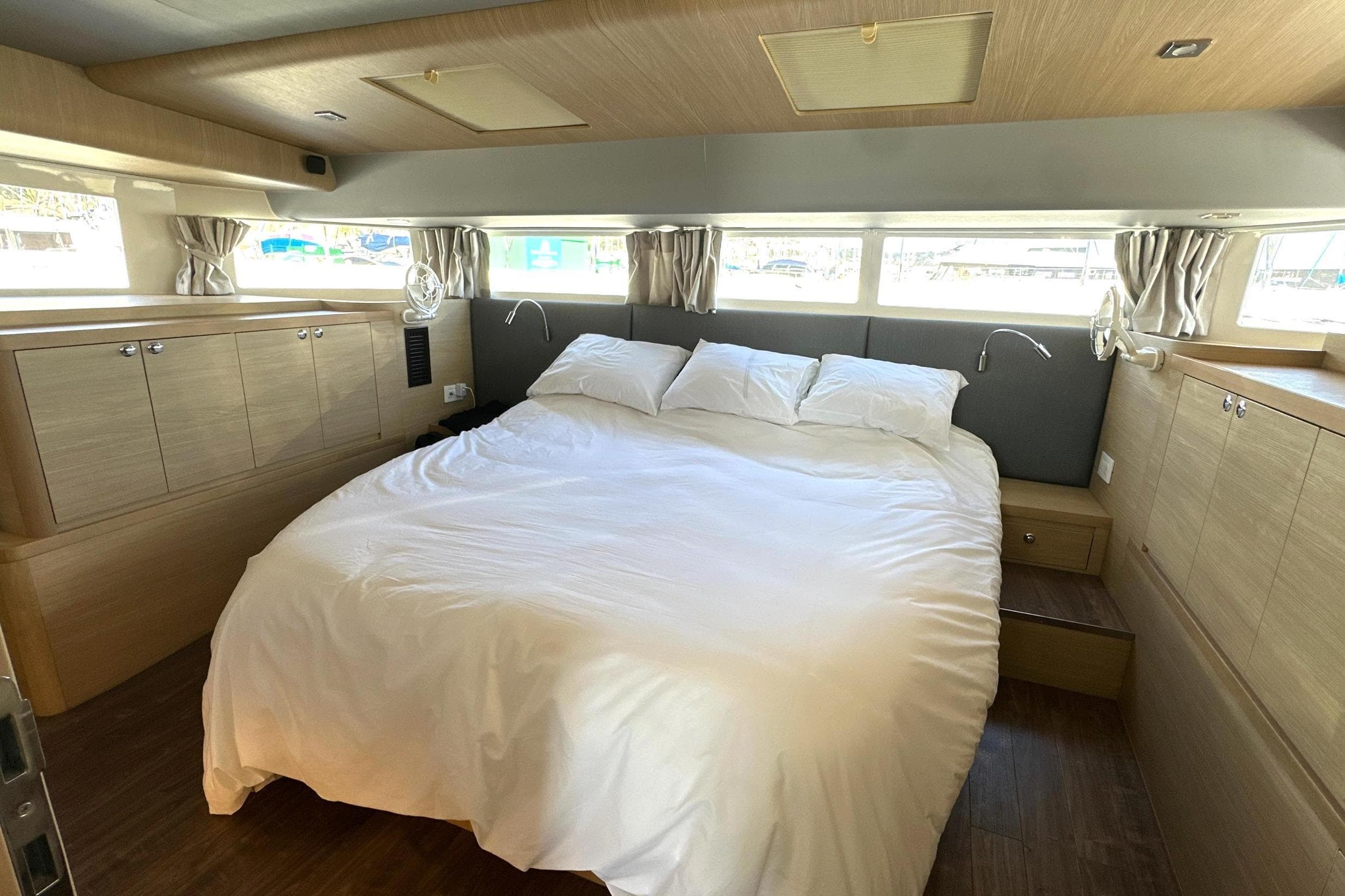 Luxurious bedroom interior of 2022 Aquila 54 Yacht with cozy bed and wooden cabinetry.