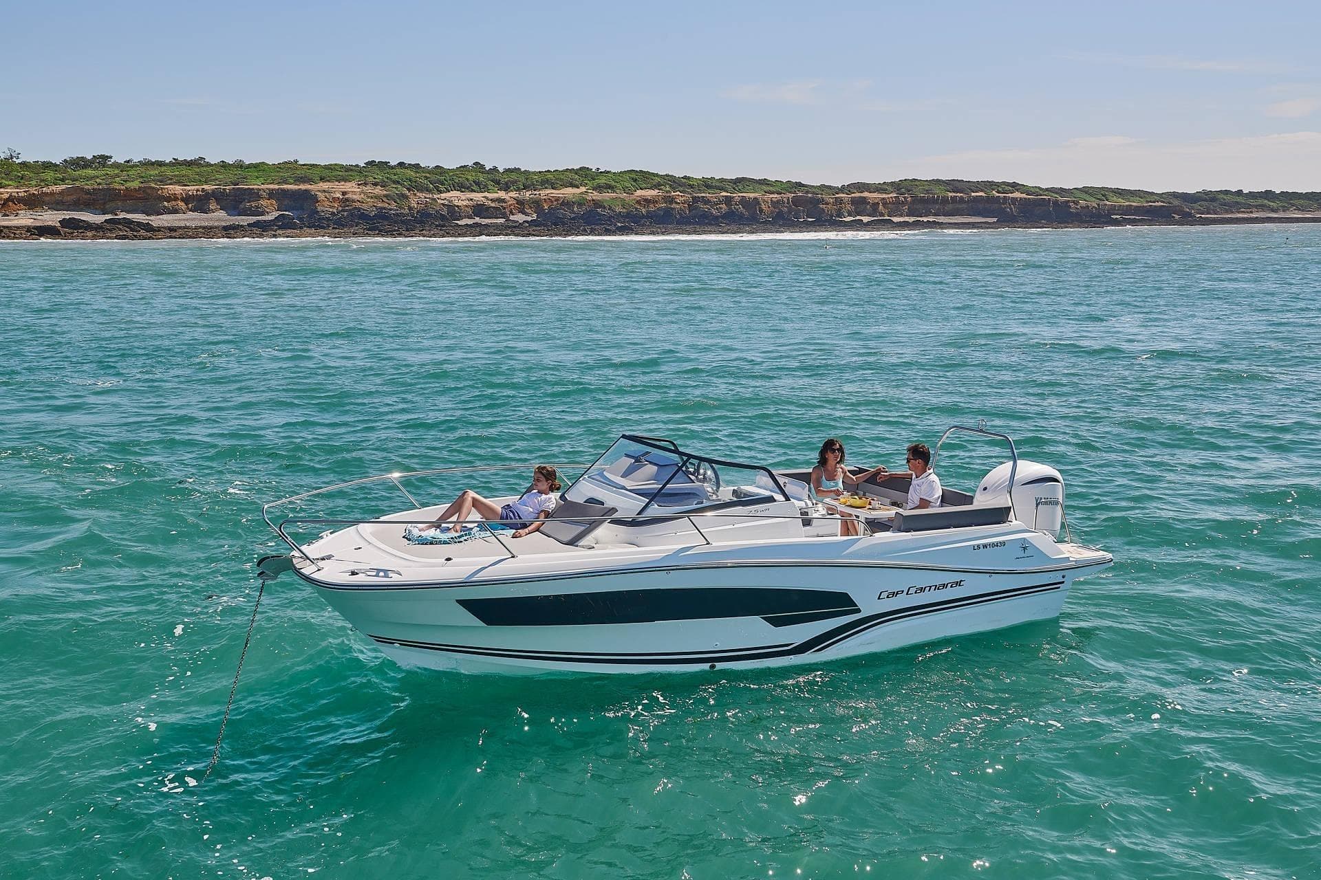 2026 Jeanneau Cap Camarat 7.5 WA Serie 3 cruising on turquoise waters near a rocky coastline.