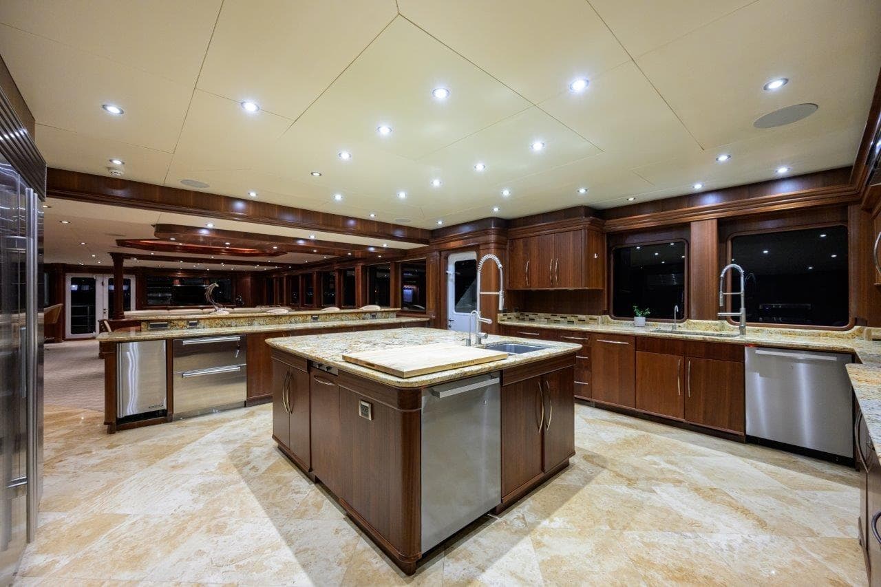 Luxurious yacht kitchen interior with wooden cabinetry, marble countertops, and modern lighting, C & G Boatworks Explorer 2011.