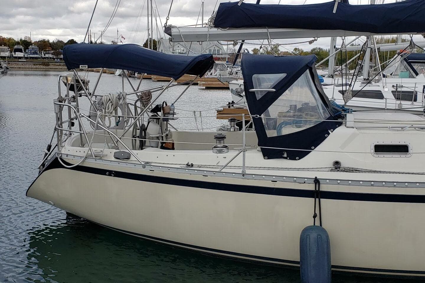 1980 CS 36 Traditional sailboat docked in a marina, featuring blue canvas covers.