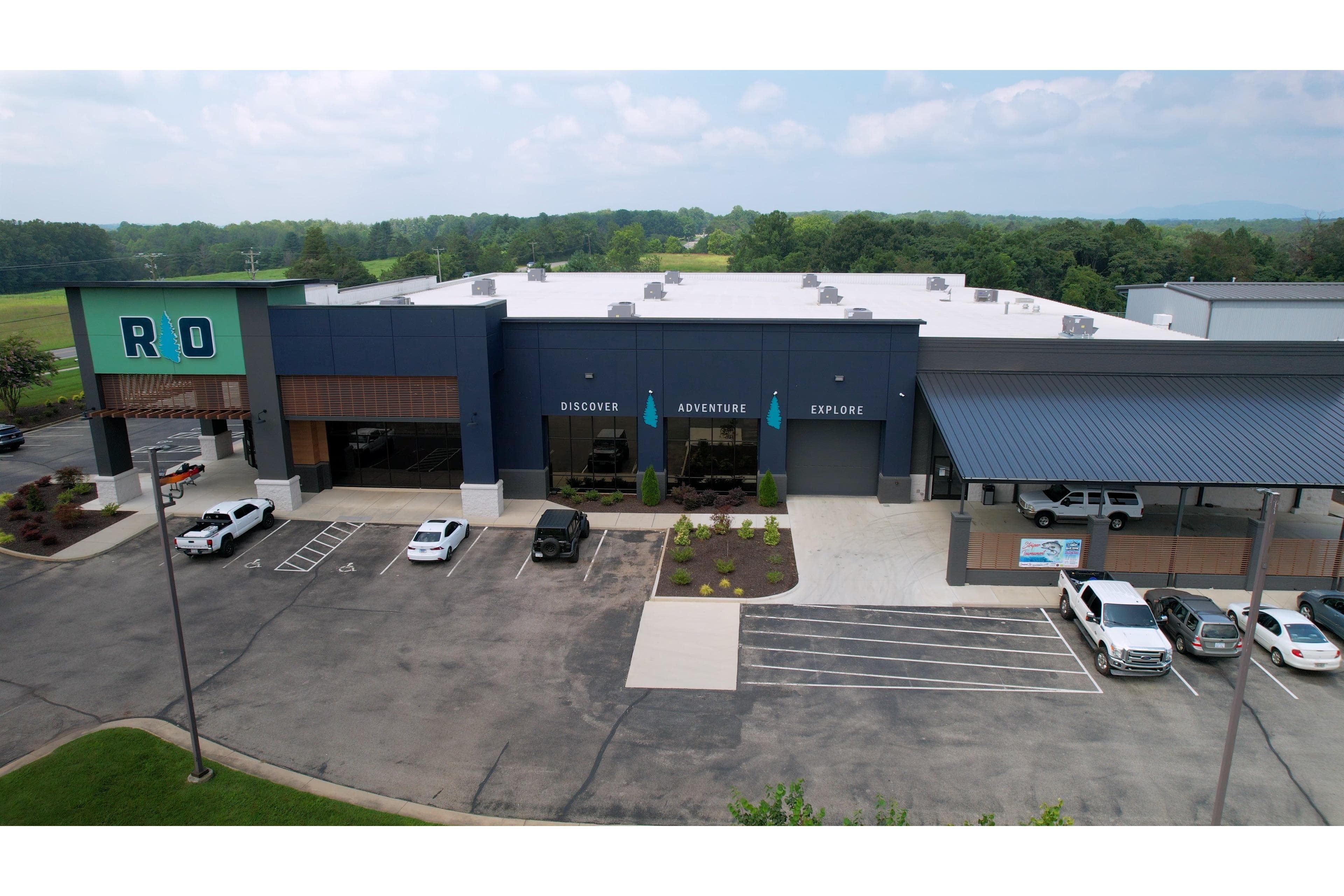 Aerial view of a modern building with parking, surrounded by greenery.