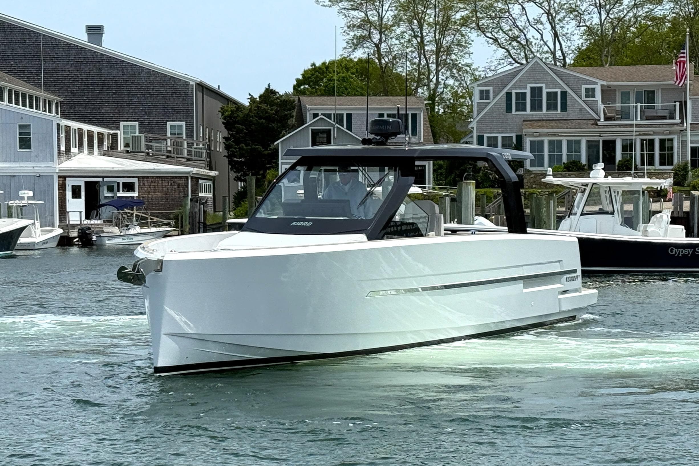 2025 Fjord 39 XP yacht cruising in a scenic harbor with waterfront homes.