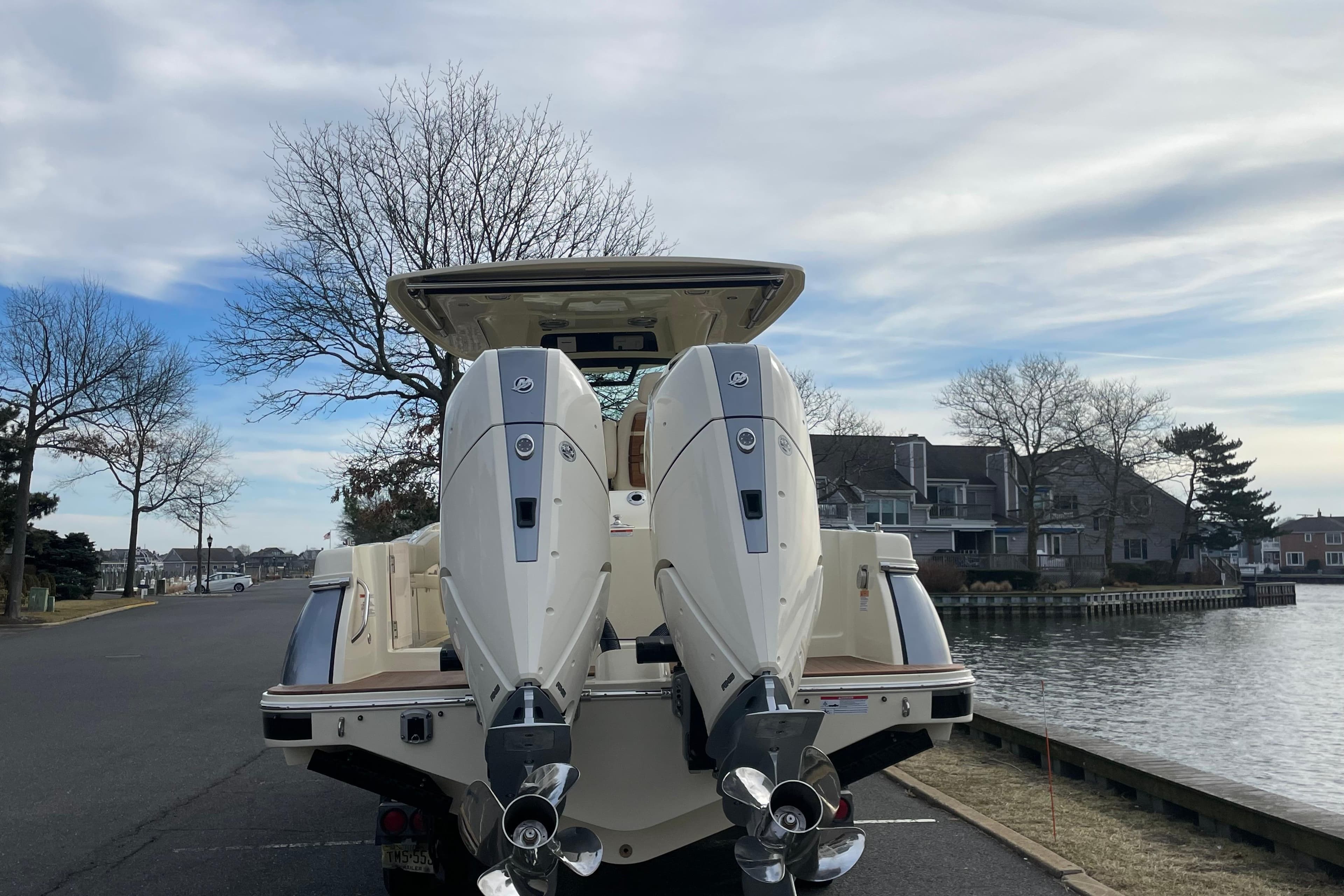 2026 Chris-Craft 310 Catalina with dual outboard engines, parked near waterfront homes.