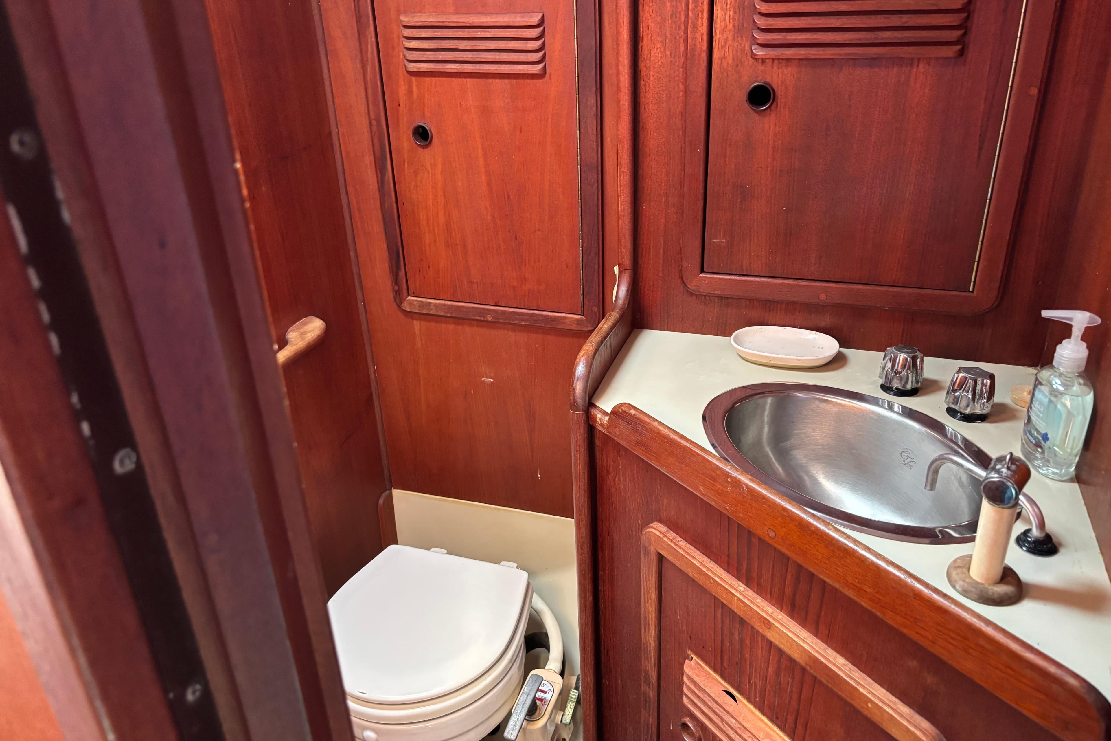 1980 C&C 40-2 yacht bathroom with wooden cabinetry, sink, and toilet.