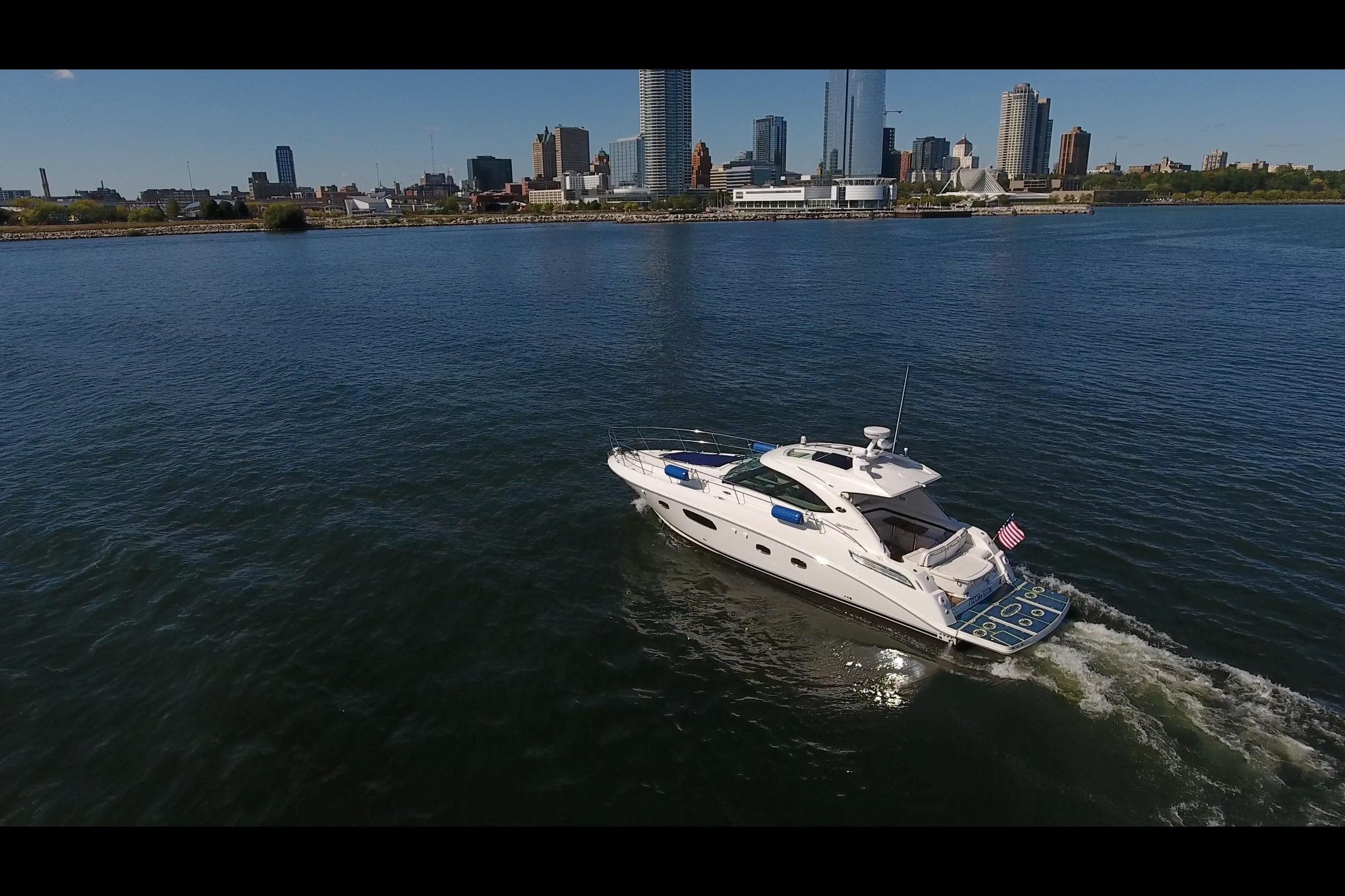 Aerial view of 2011 Sea Ray 470 Sundancer yacht cruising near city skyline.