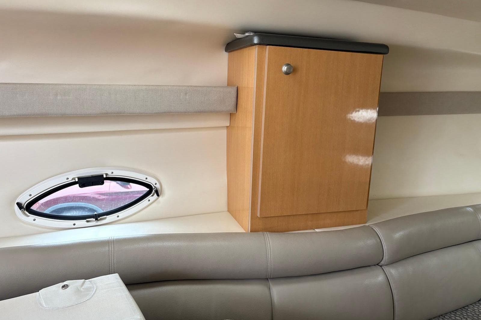 Interior of 2004 Maxum 3100 SE boat with wooden cabinet and oval window.