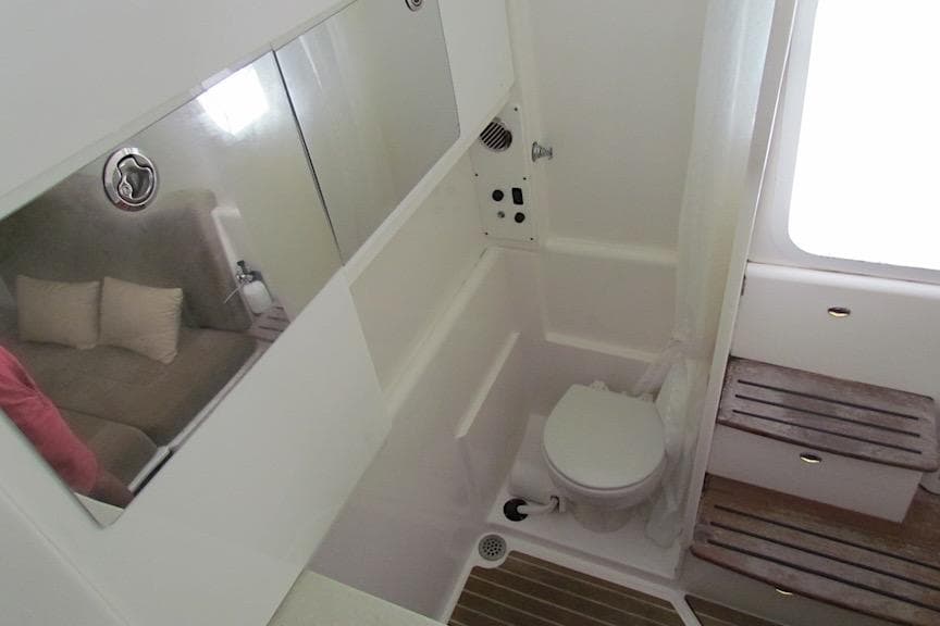 Interior of 2016 Everglades 435 Center Console boat, featuring a compact bathroom with toilet and mirror.