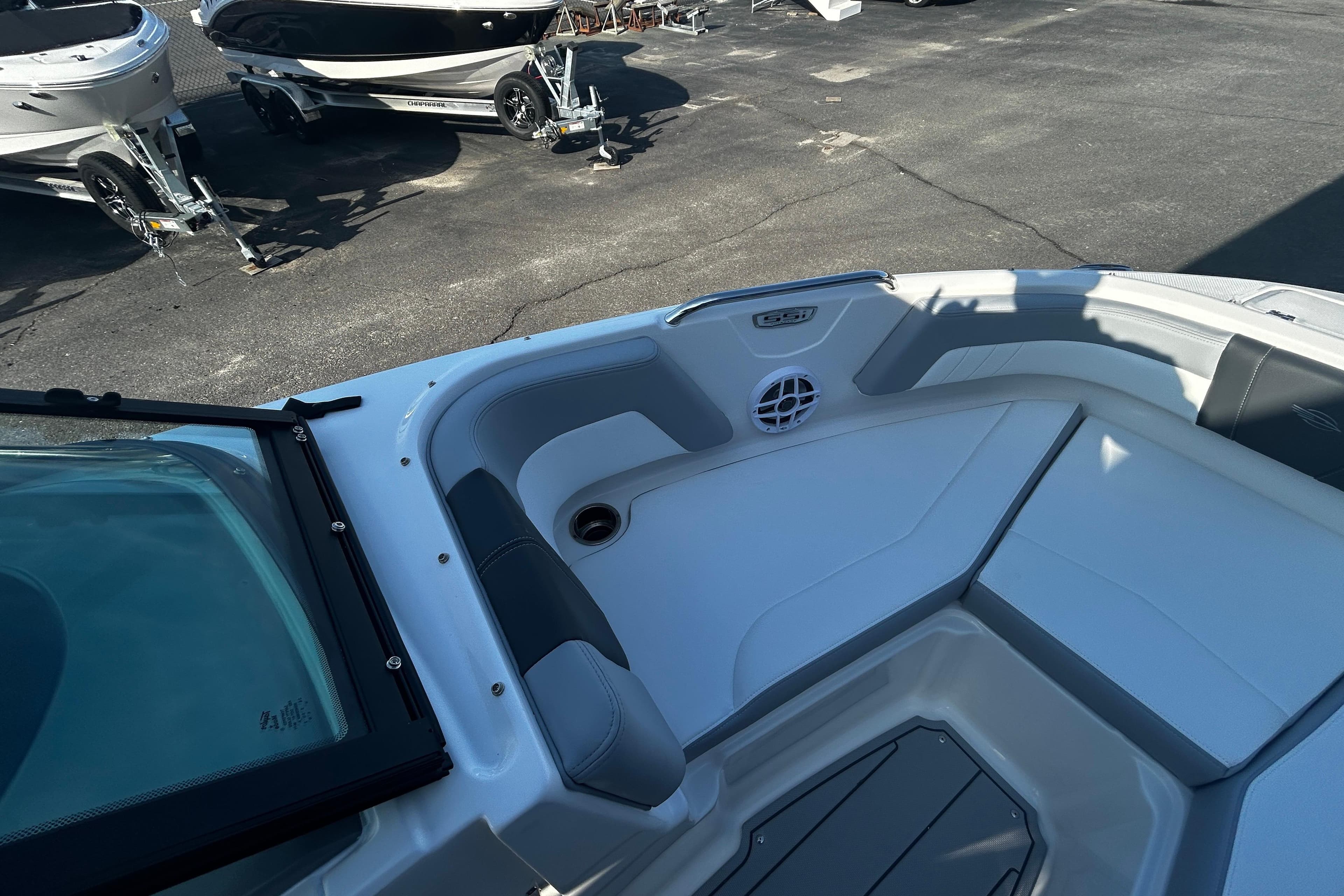 2026 Chaparral 21 SSi OB boat interior with seating and speaker, parked on asphalt.