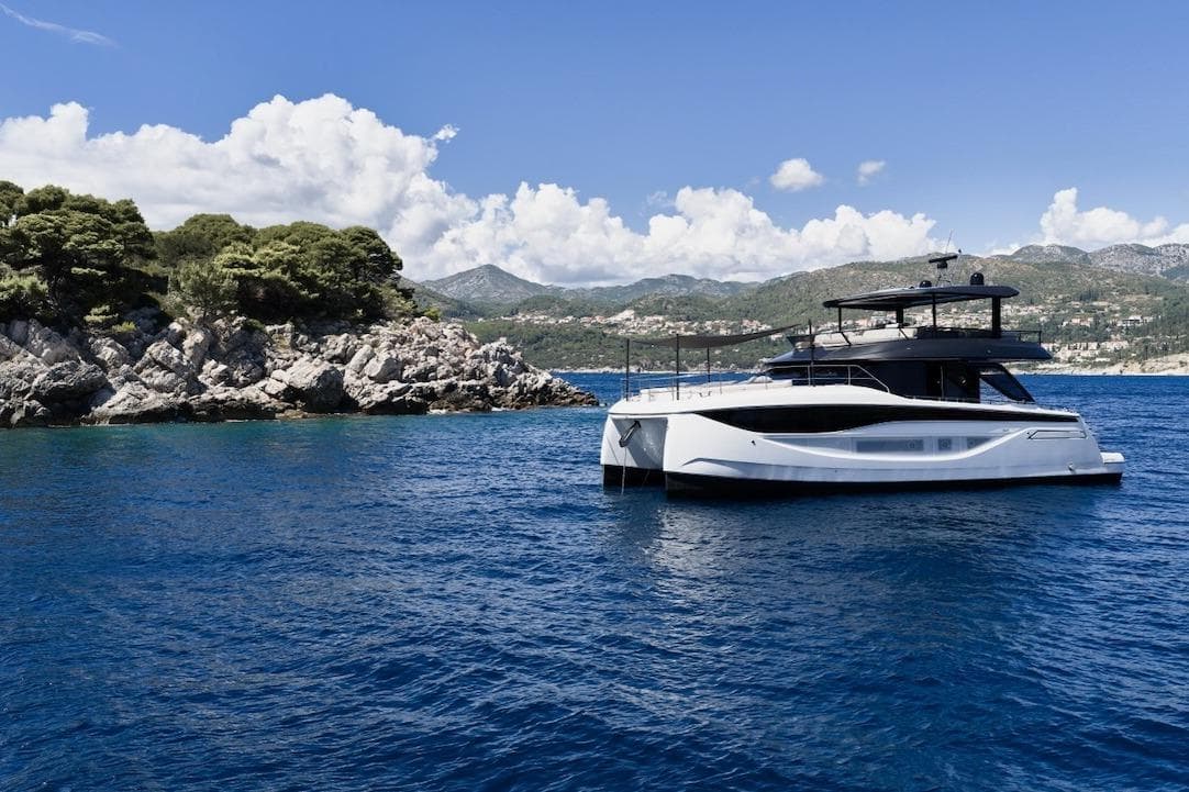 Luxury Prestige M7 yacht cruising near rocky coastline, 2025 model.