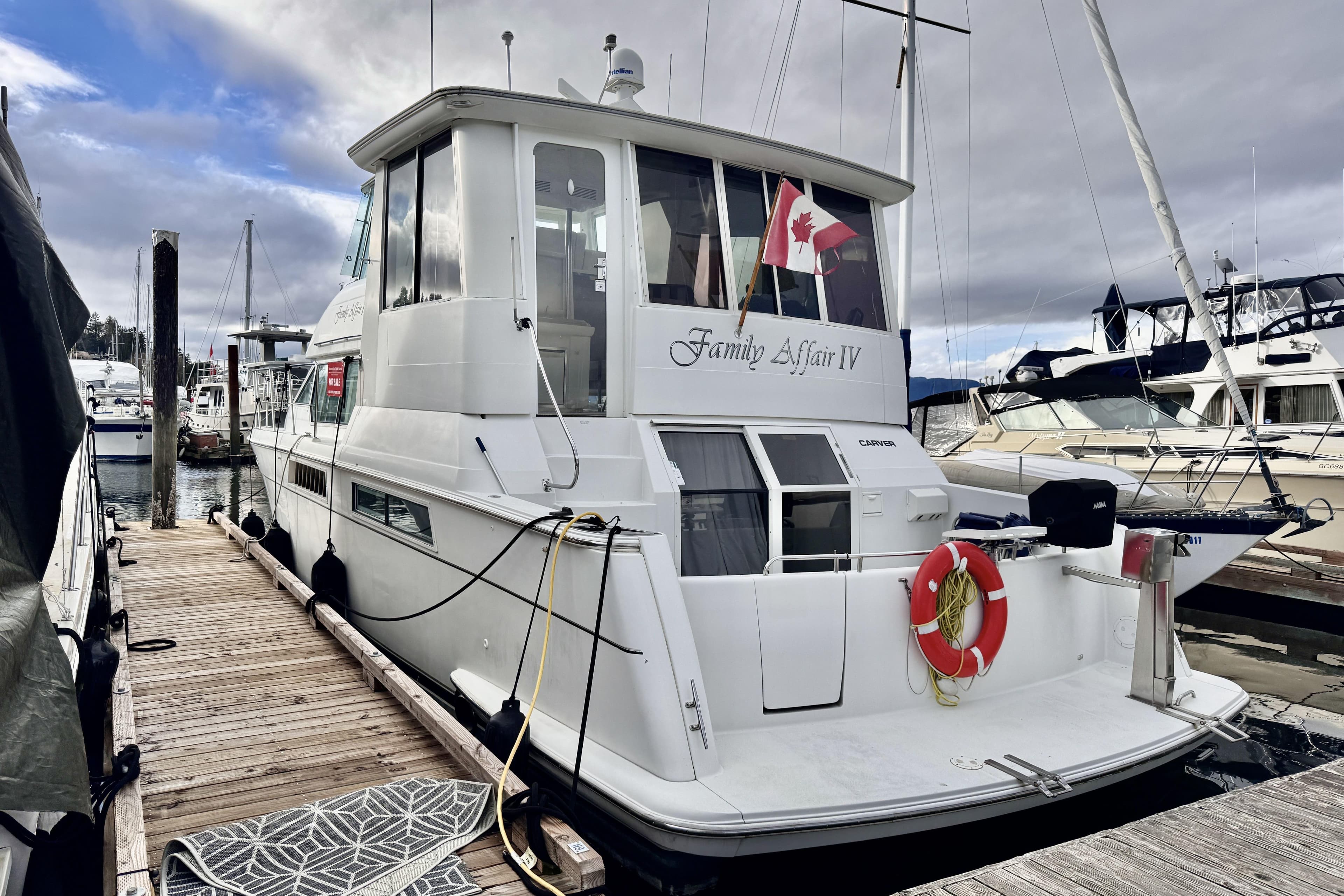 1997 Carver 500 Cockpit Motor Yacht docked, featuring Canadian flag and lifebuoy.