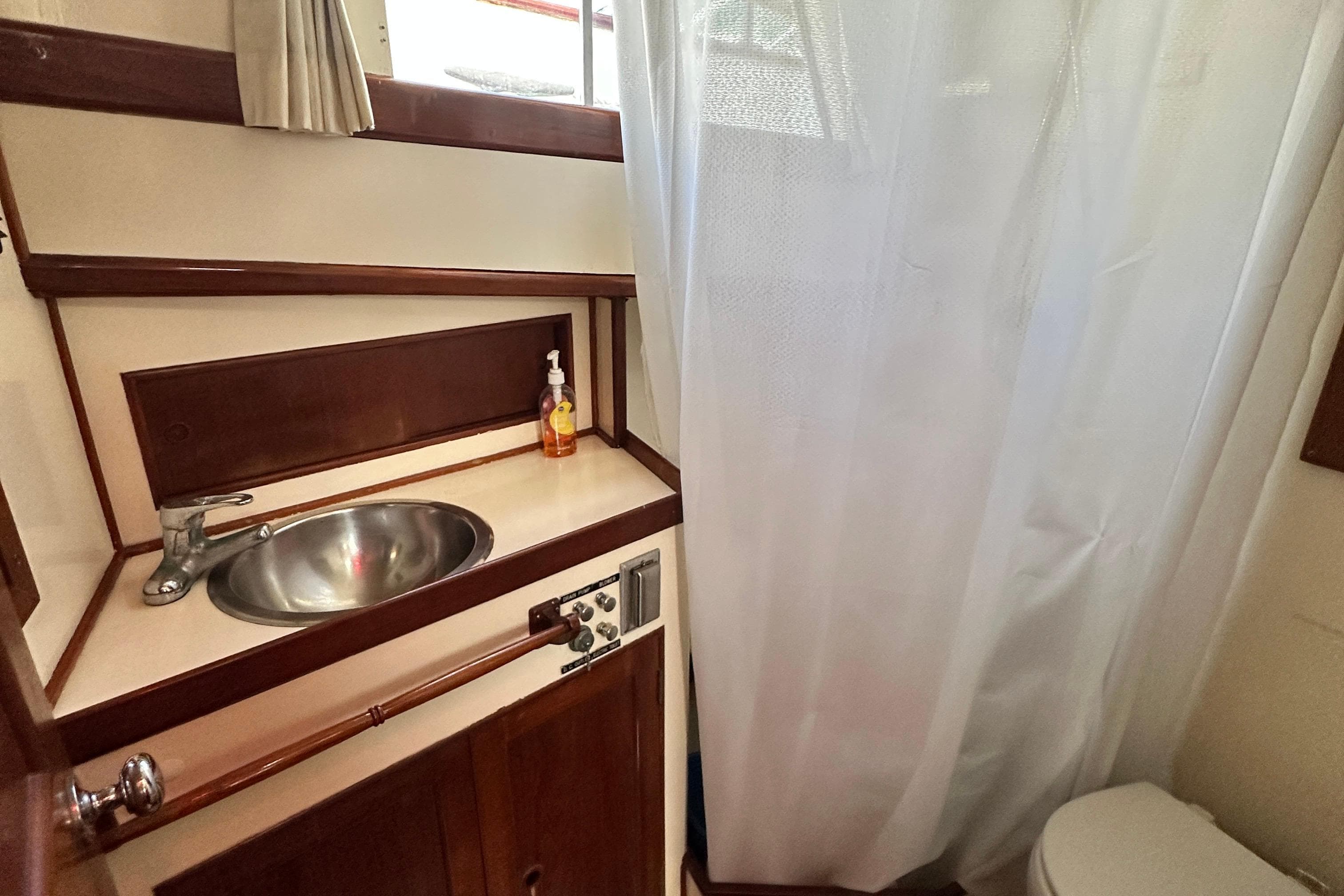 1980 Island Gypsy yacht bathroom with sink, faucet, and shower curtain.