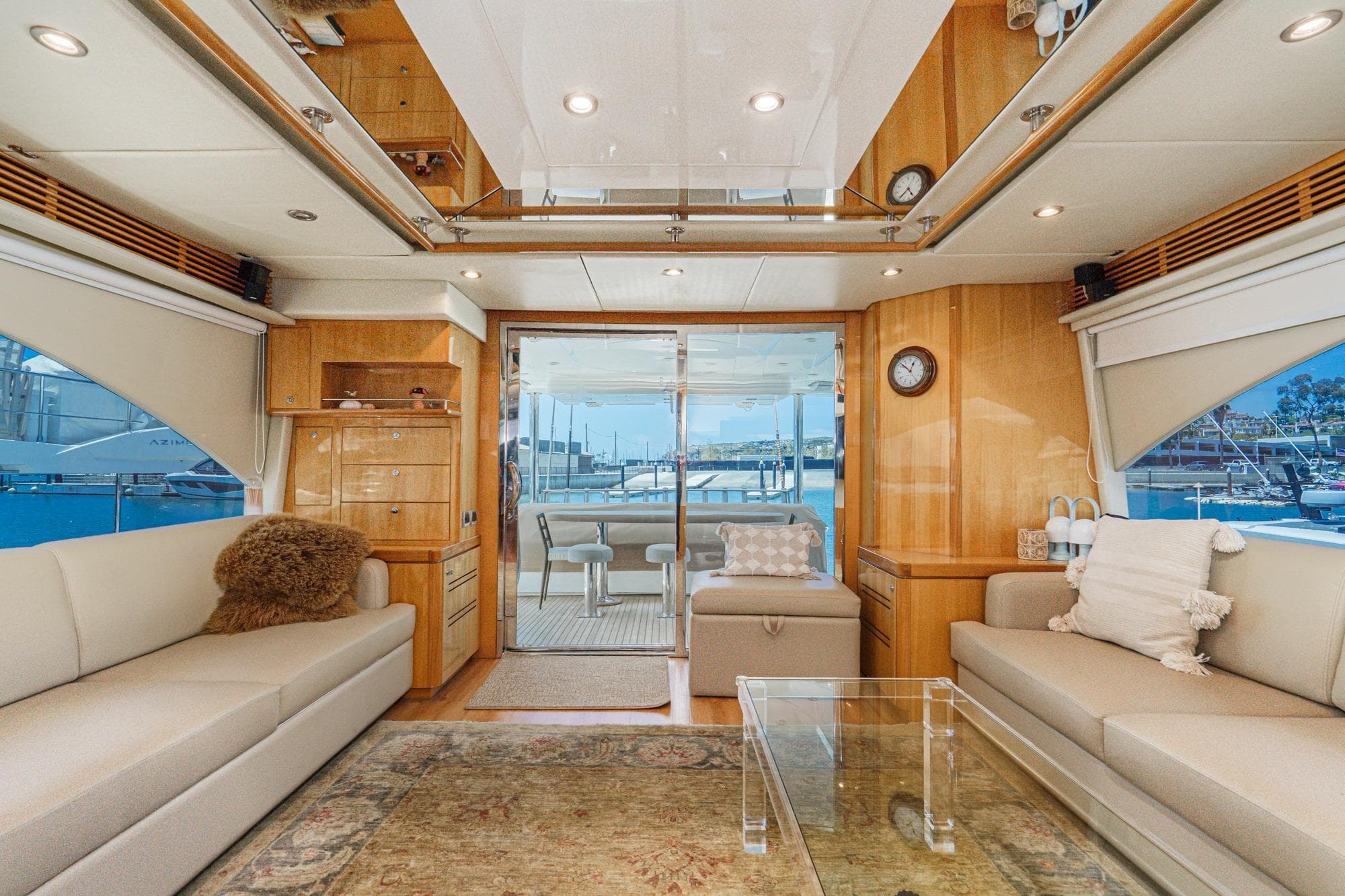 Luxurious Mystica 82 yacht interior, featuring elegant seating and a scenic marina view.