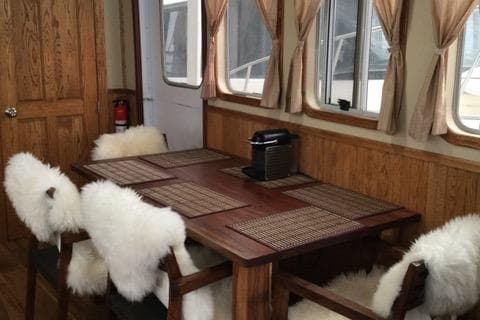 Dining area in 2013 Custom Trawler 45 with wooden table, cushioned chairs, and coffee maker.