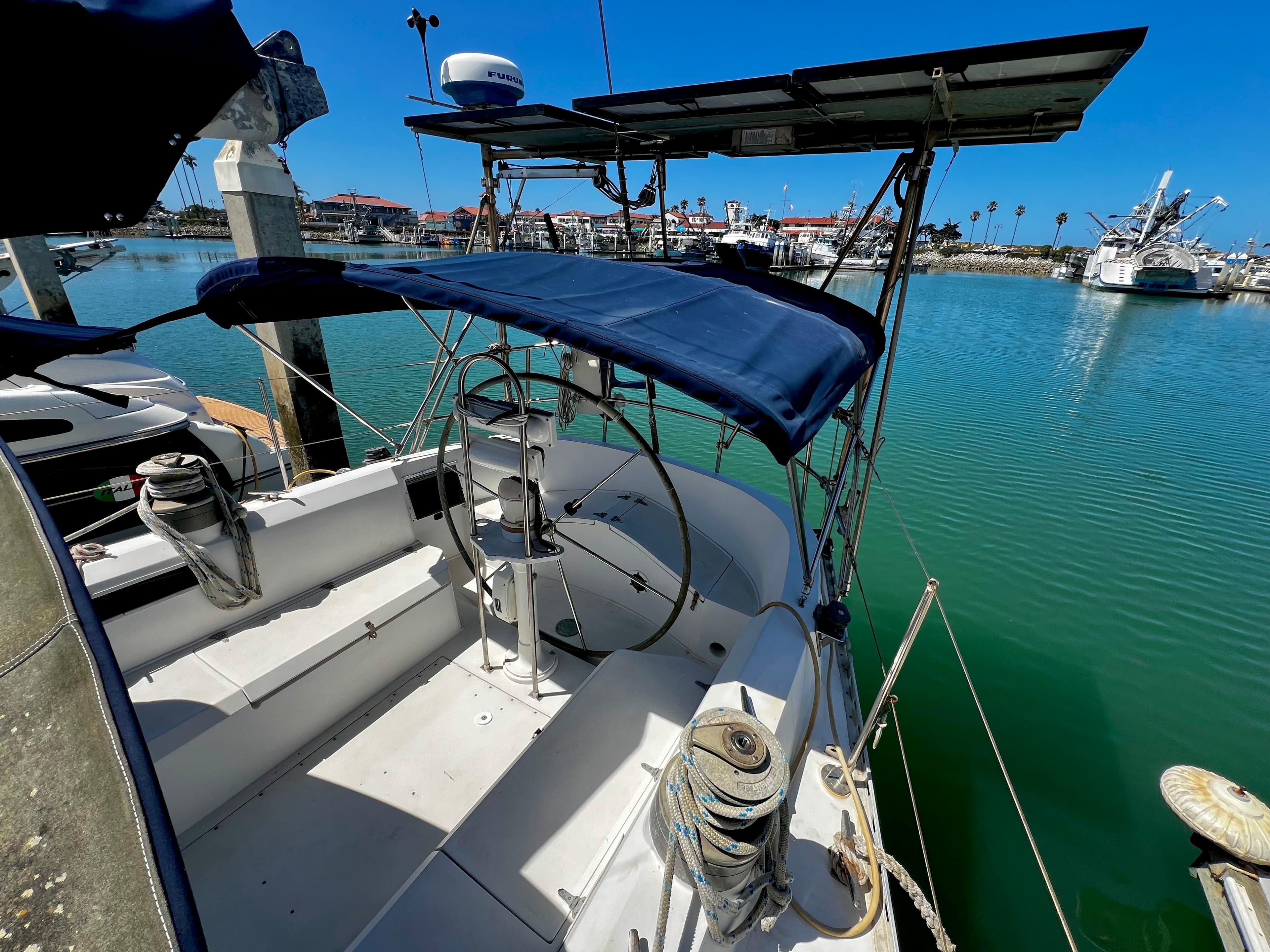 1981 Cheoy Lee Golden Wave yacht docked in a marina, featuring a blue canopy and steering wheel.