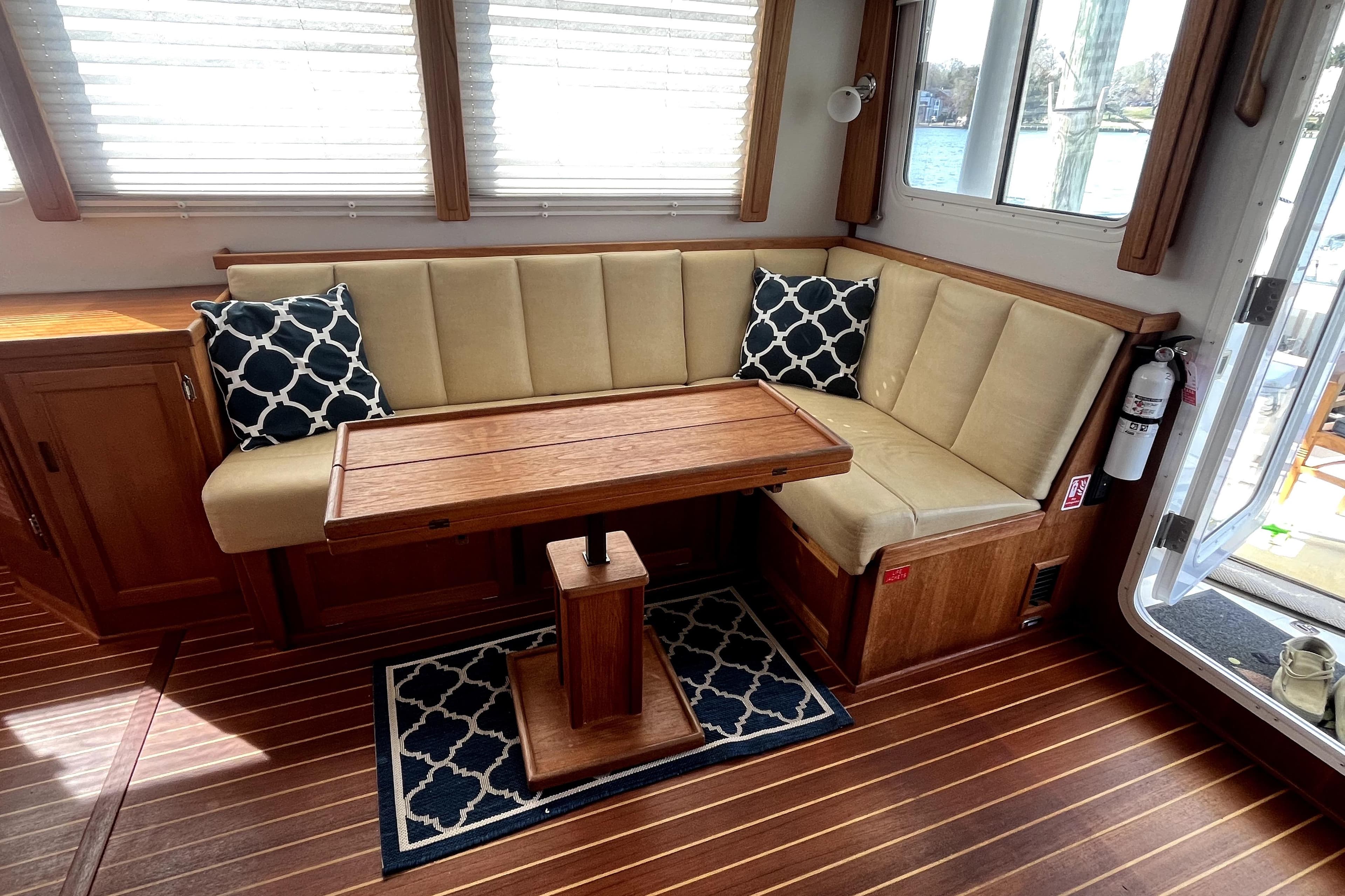 Cozy interior of 2008 Nordic Tug 42 with cushioned seating and wooden table.