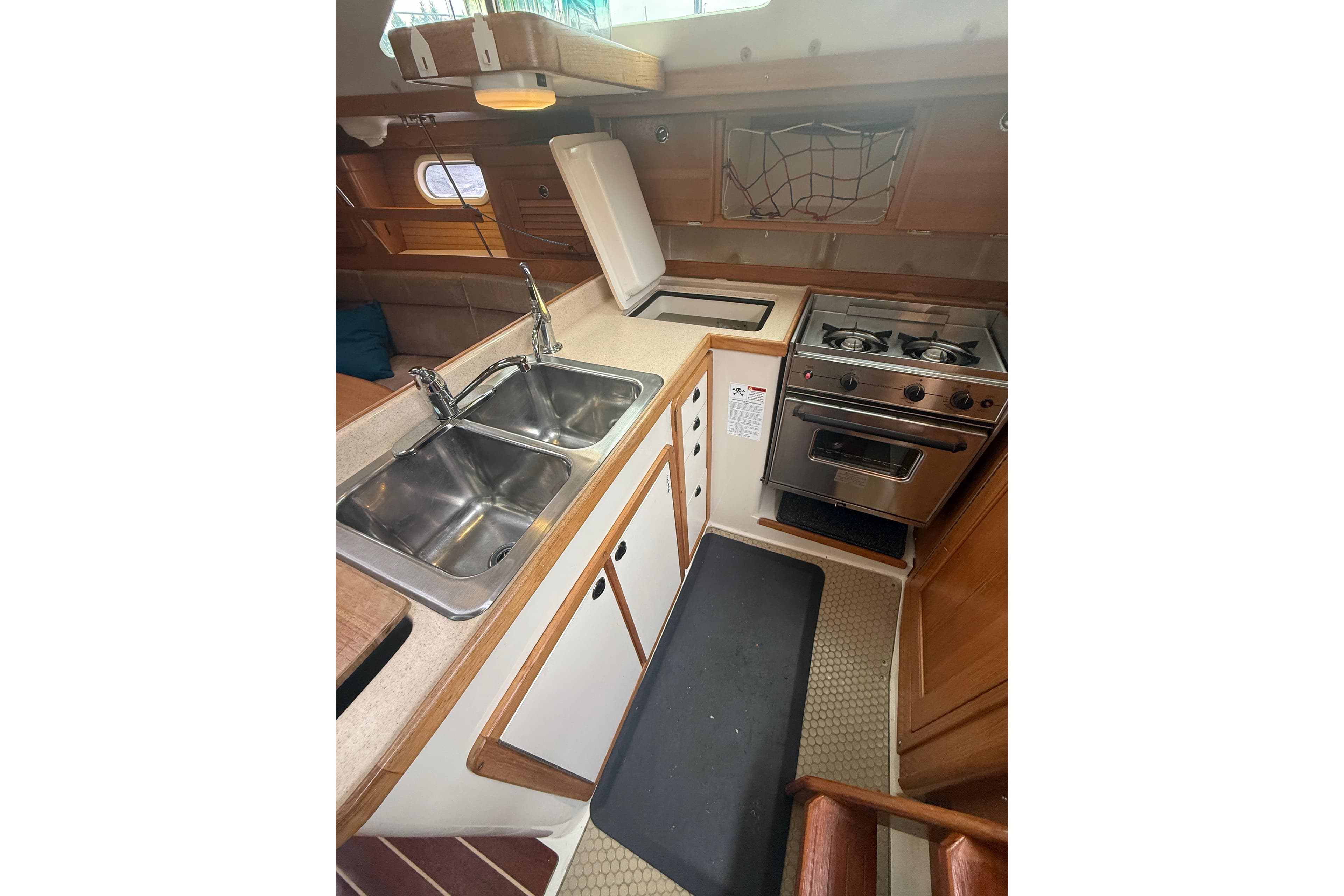 2003 Catalina 34 MkII yacht kitchen with dual sinks, stove, and wooden cabinetry.