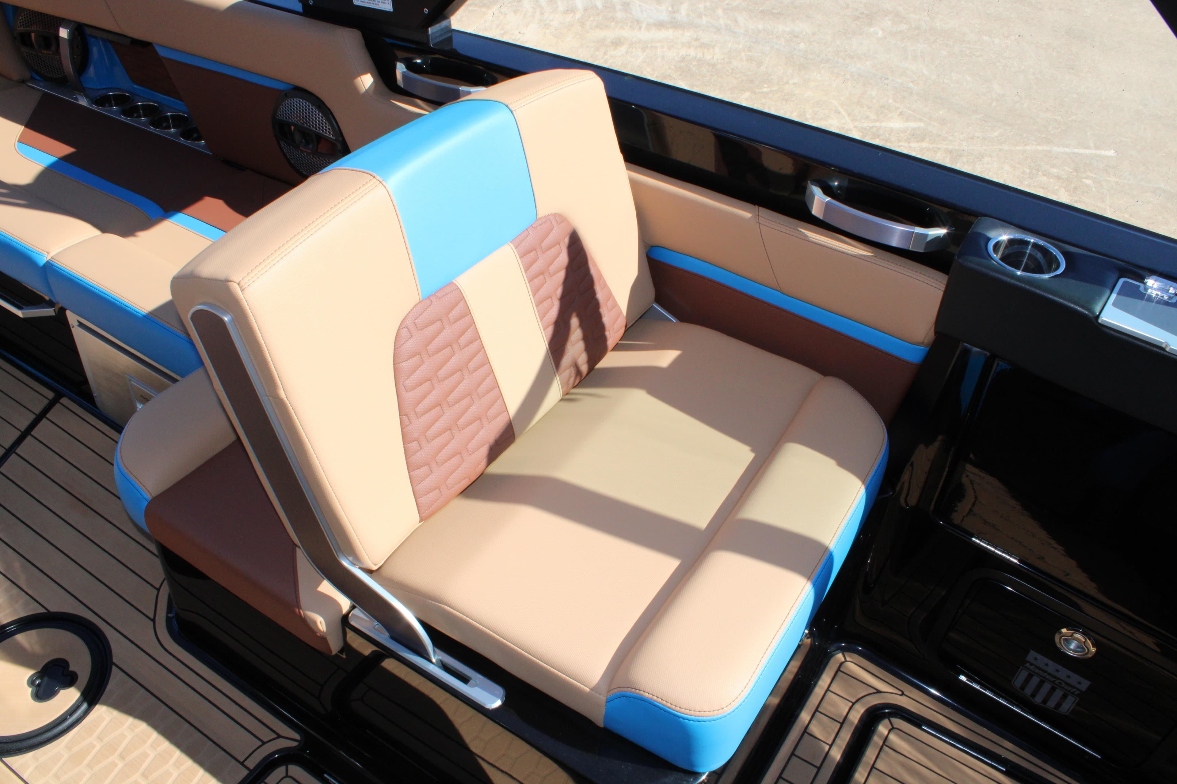 2023 MasterCraft X26 boat interior with tan and blue seating, cup holders, and sleek design.