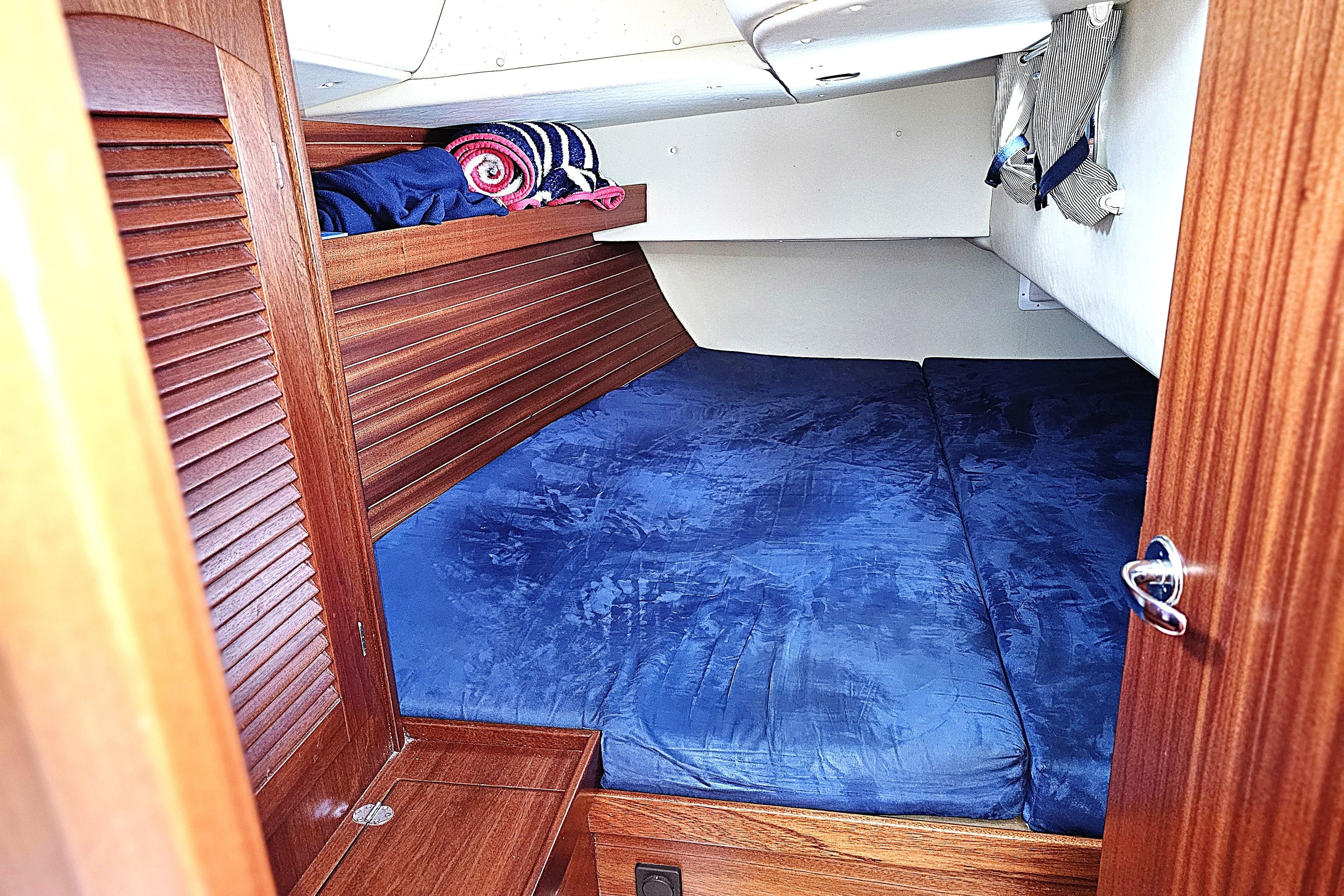 Cozy cabin interior of a 2006 Maxi 1100 sailboat with blue bedding.
