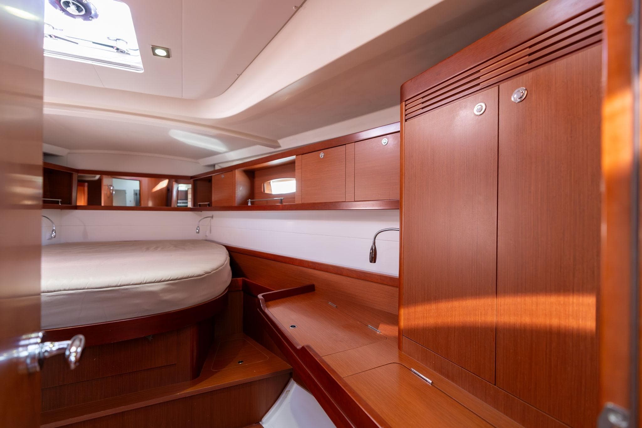 Luxurious interior of 2013 Beneteau Oceanis 50 yacht with wooden cabinetry and cozy bed.