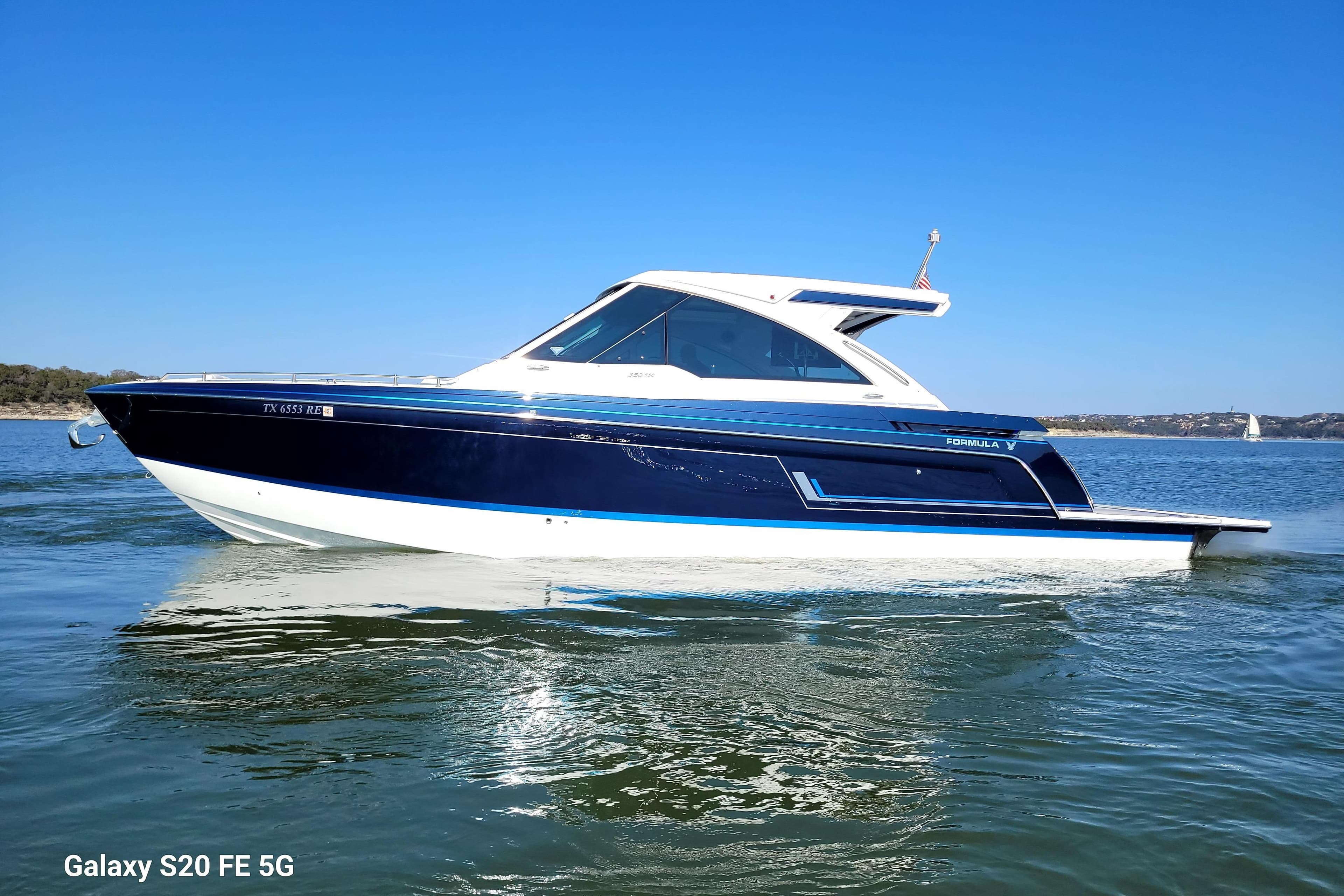 2023 Formula 380 Super Sport Crossover I/O boat on calm water under clear blue sky.